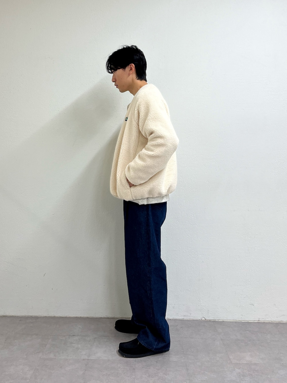 グレー系のスウェット、ホワイト系のブルゾン、ブルー系のデニムパンツを着用したメンズの冬コーディネートの2枚目の写真