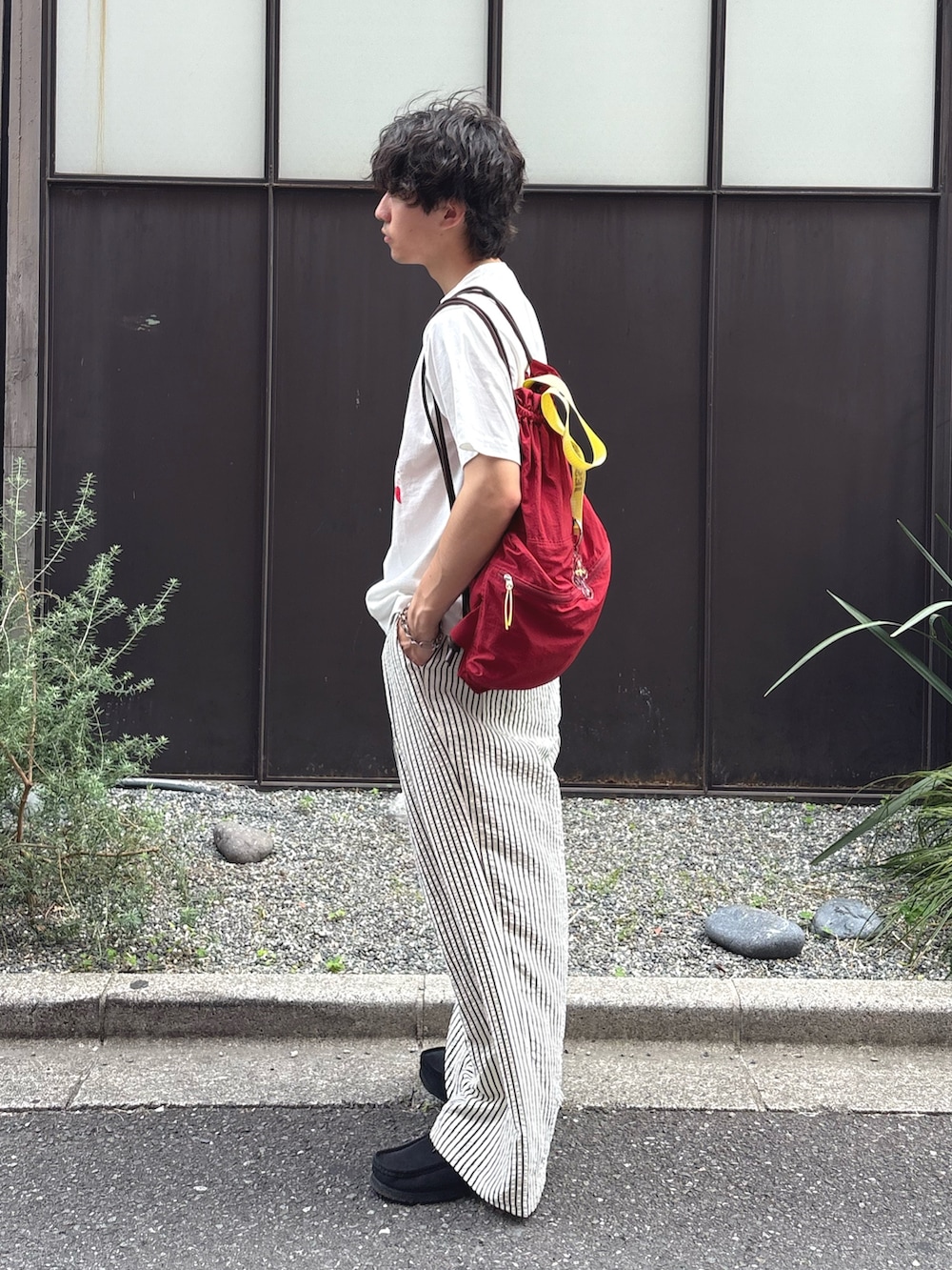 ホワイト系のTシャツ/カットソー、レッド系のバックパック/リュック、ホワイト系のその他パンツを着用したメンズの春コーディネートの2枚目の写真