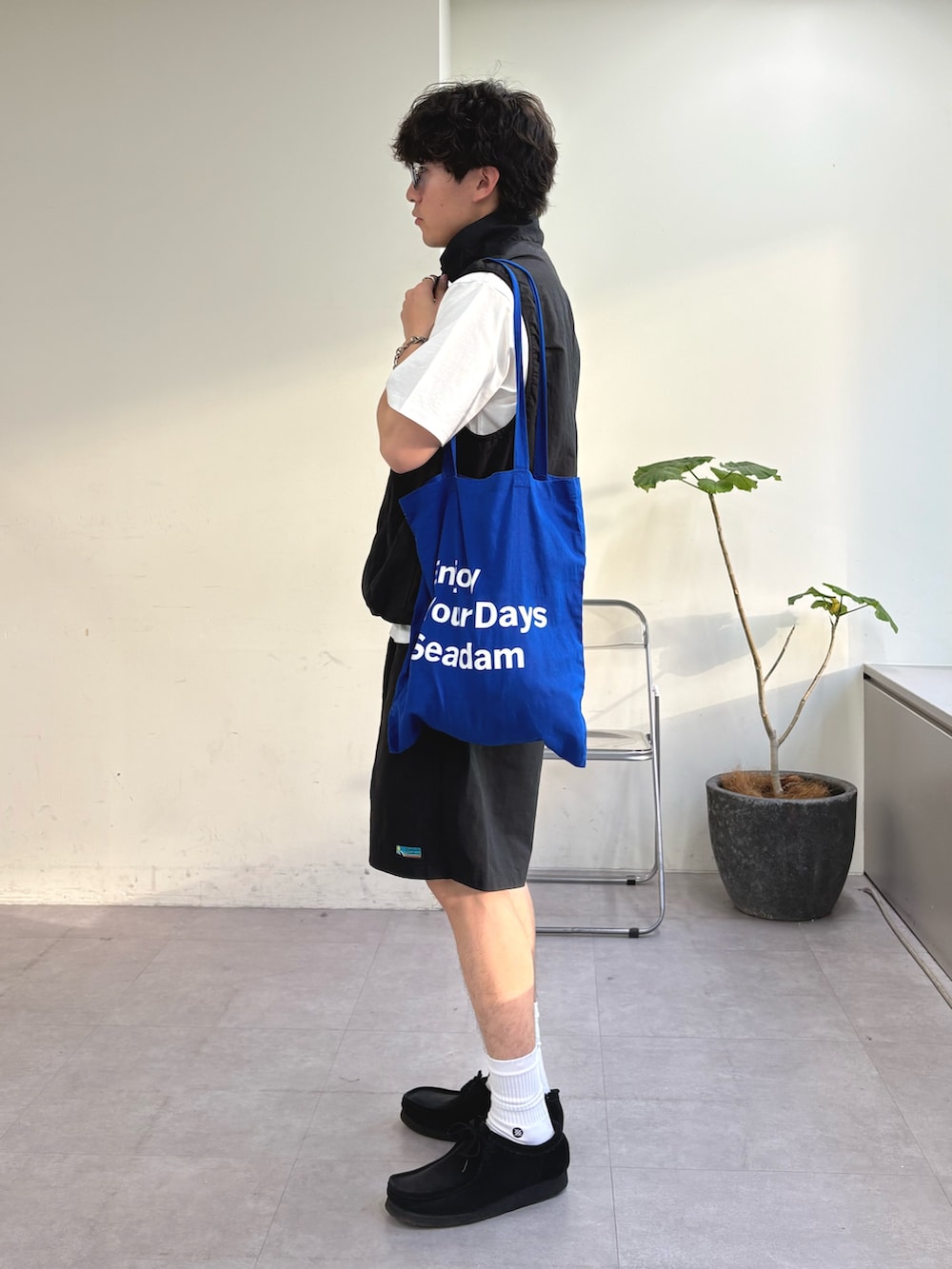 ブラック系のベスト、ブルー系のトートバッグ、ブラック系のその他パンツを着用したメンズの春コーディネートの2枚目の写真