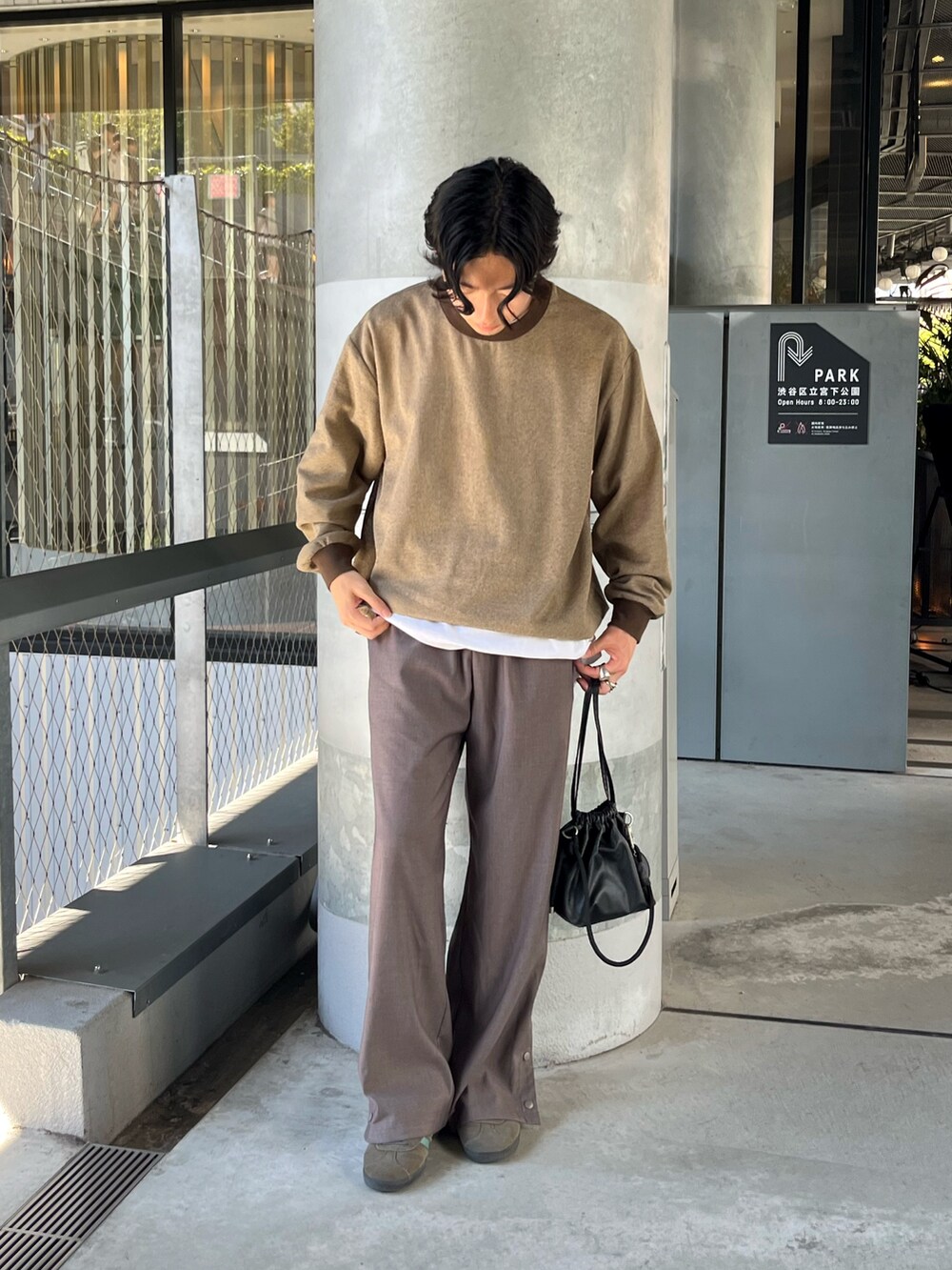 ブラウン系のTシャツ/カットソー、グレー系のスラックス、ブラック系のショルダーバッグを着用したメンズの秋コーディネートの2枚目の写真