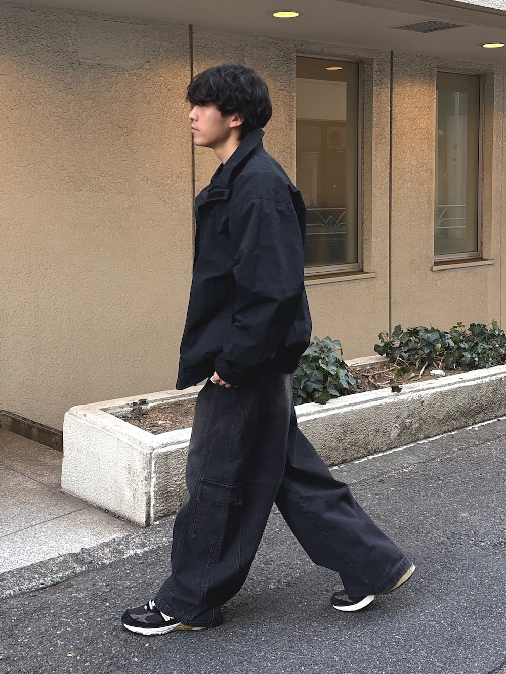 ブラック系のナイロンジャケット、イエロー系のスウェット、ブラック系のデニムパンツを着用したメンズの冬コーディネートの2枚目の写真