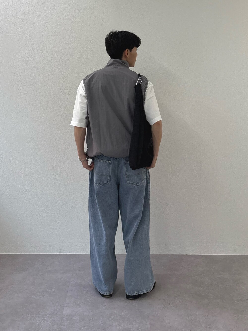 グレー系のベスト、ブルー系のデニムパンツ、ホワイト系のTシャツ/カットソーを着用したメンズの春コーディネートの2枚目の写真