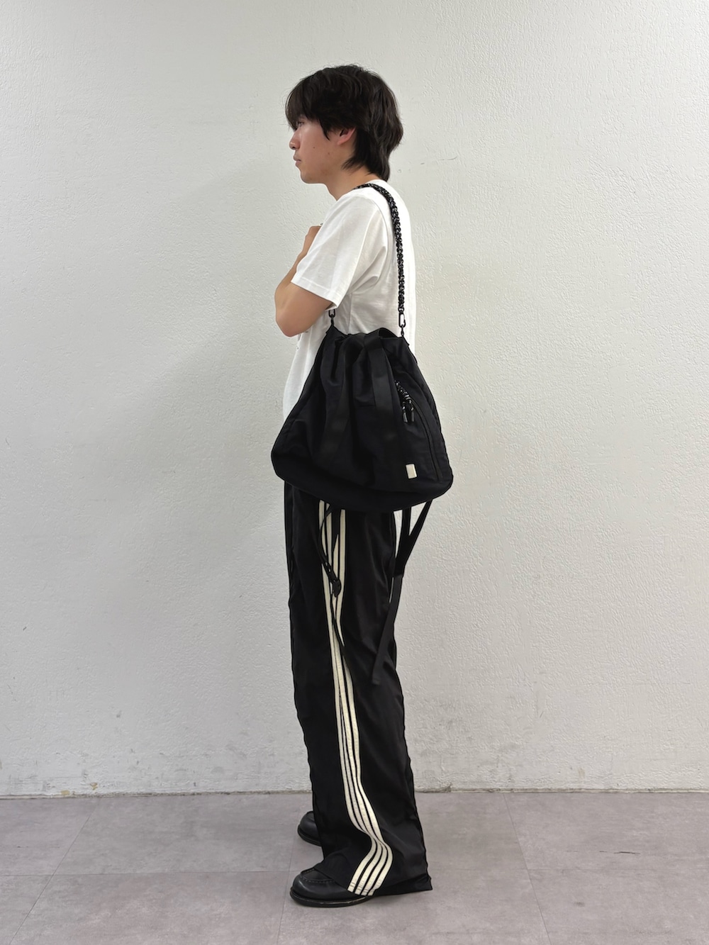 ホワイト系のTシャツ/カットソー、ブラック系のトートバッグ、ブラック系のスウェットパンツを着用したメンズの春コーディネートの2枚目の写真