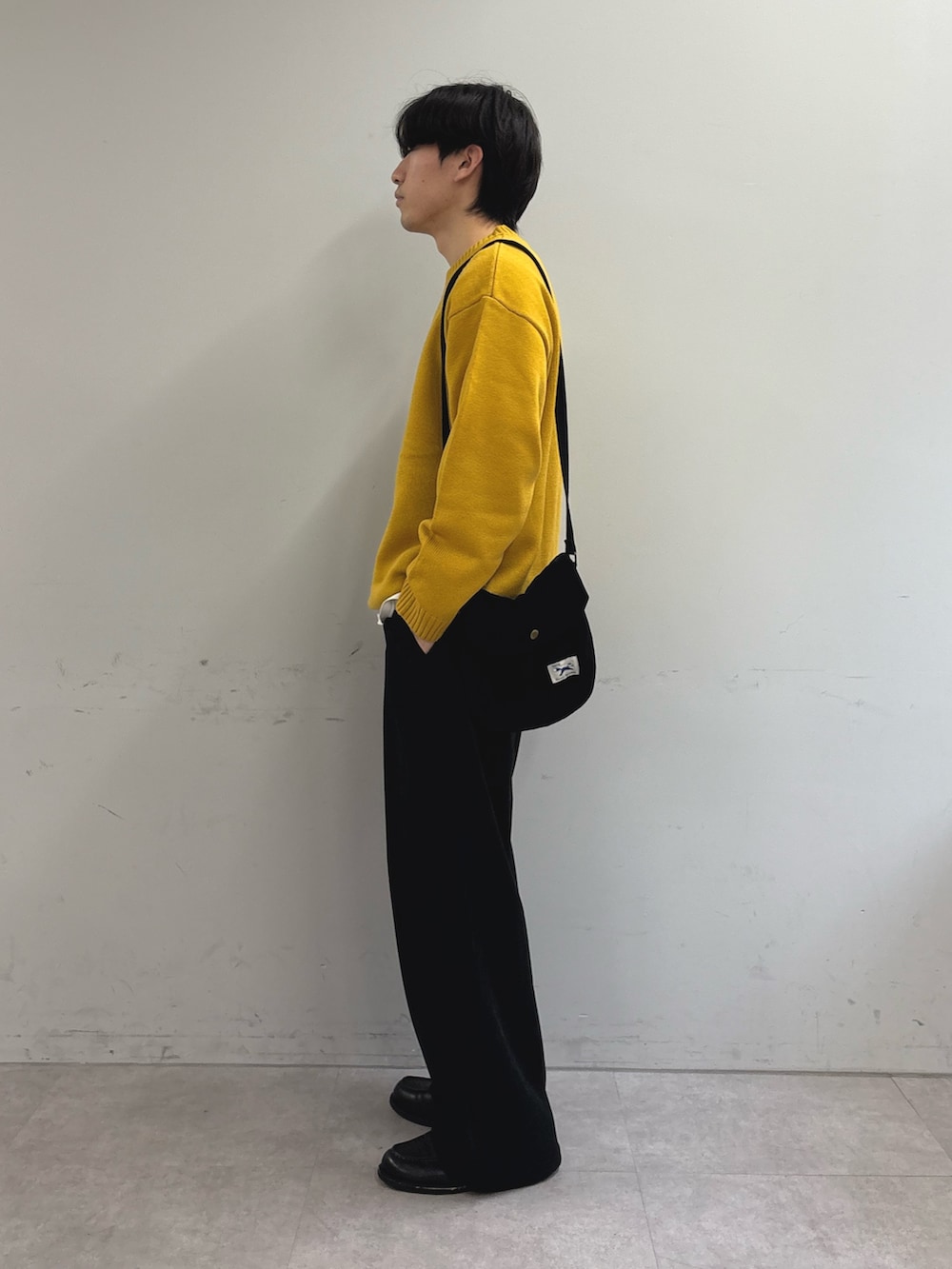 イエロー系のニット/セーター、ブラック系のショルダーバッグ、ブラック系のその他パンツを着用したメンズの冬コーディネートの2枚目の写真