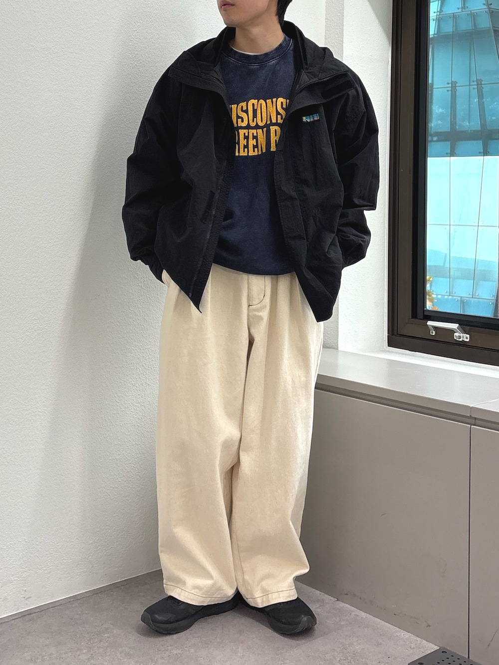 ブラック系のナイロンジャケット、ブルー系のスウェット、ホワイト系のデニムパンツを着用したメンズの秋コーディネートの2枚目の写真