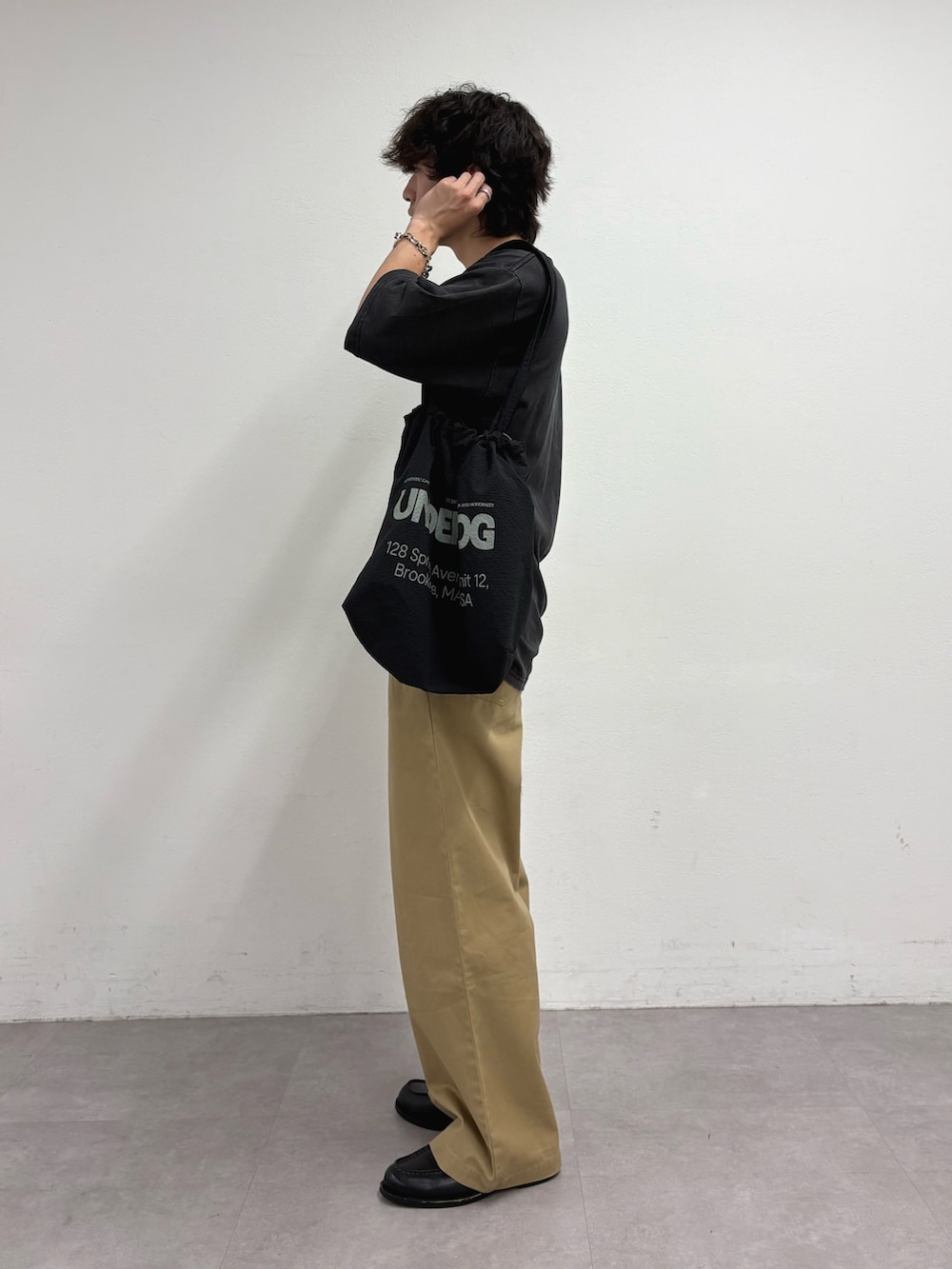 ブラック系のTシャツ/カットソー、ブラック系のトートバッグ、ベージュ系のデニムパンツを着用したメンズの夏コーディネートの2枚目の写真