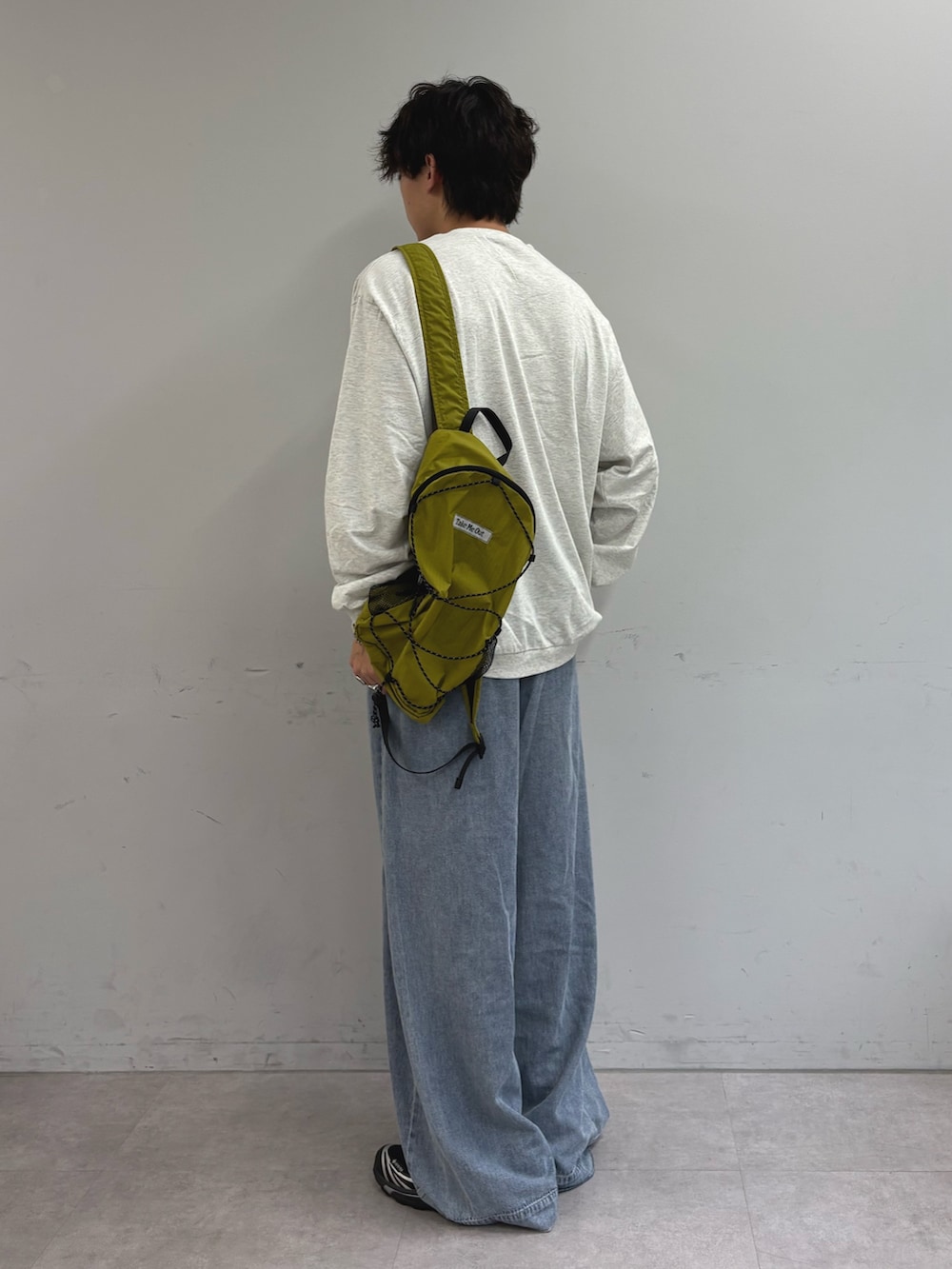グレー系のTシャツ/カットソー、グリーン系のバックパック/リュック、ブルー系のデニムパンツを着用したメンズの秋コーディネートの2枚目の写真
