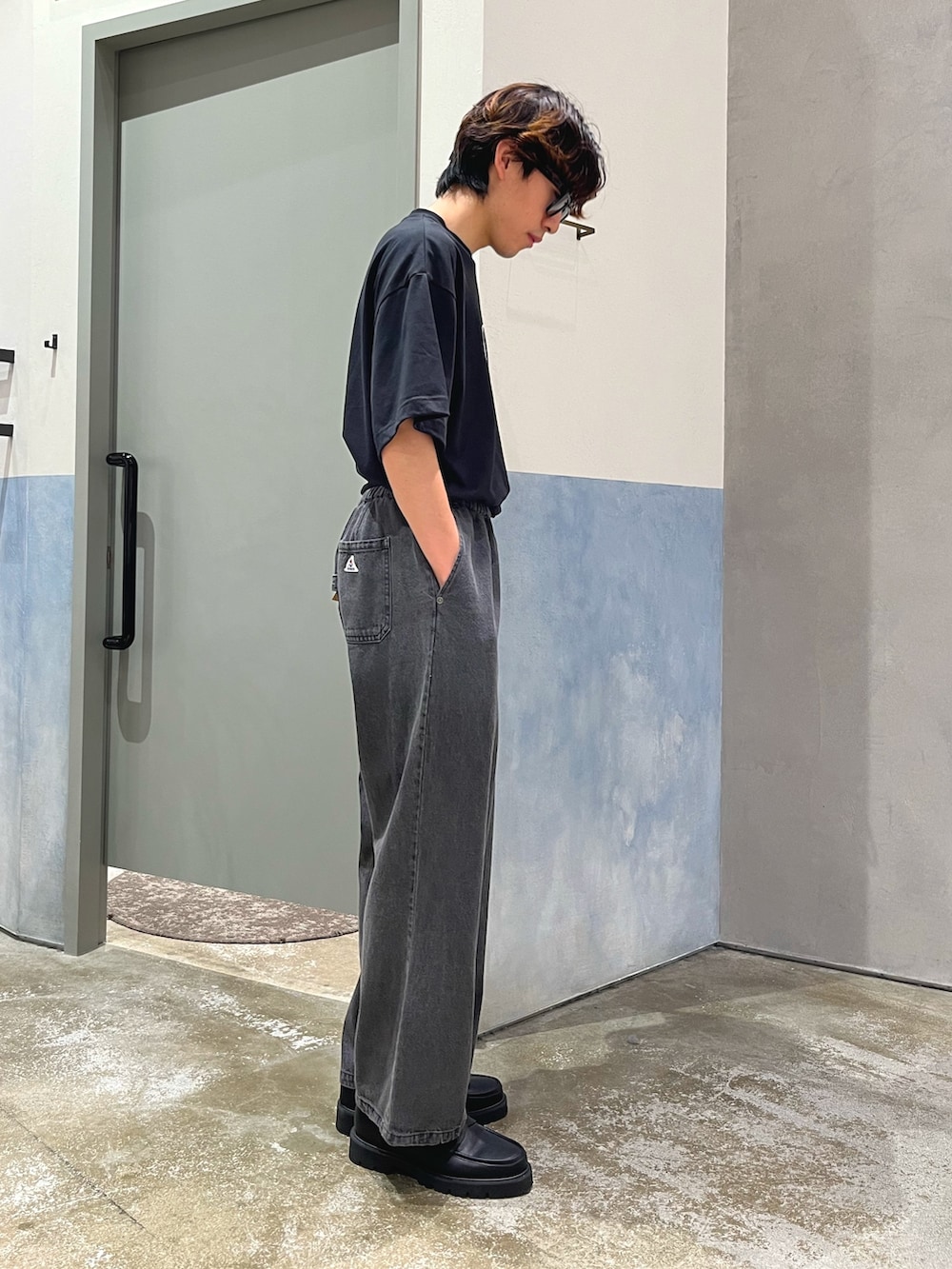 ブラック系のデニムパンツ、ブラック系のローファー、ブラック系のTシャツ/カットソーを着用したメンズの夏コーディネートの2枚目の写真