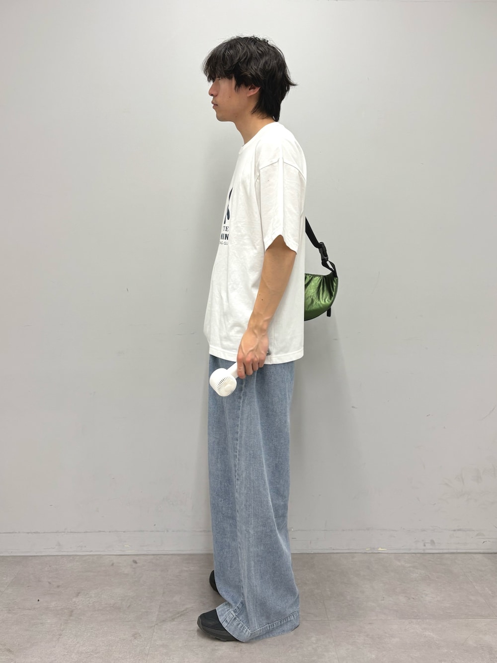 ブルー系のデニムパンツ、グリーン系のボディバッグ/ウエストポーチ、ホワイト系のTシャツ/カットソーを着用したメンズの春コーディネートの2枚目の写真