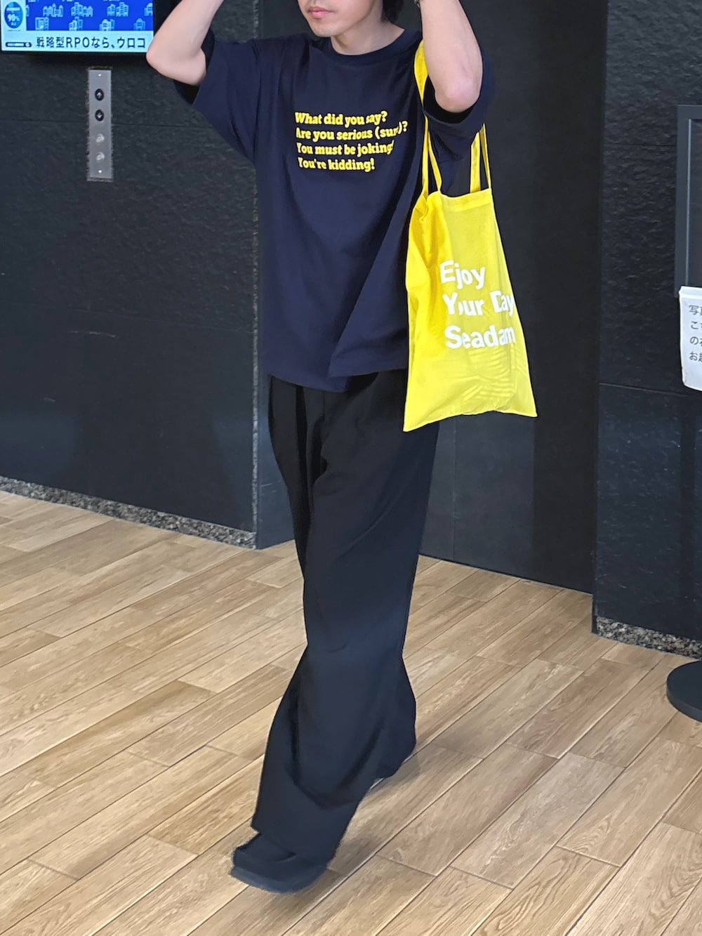 ブルー系のTシャツ/カットソー、ブラック系のトートバッグ、ブラック系のスラックスを着用したメンズの春コーディネートの2枚目の写真