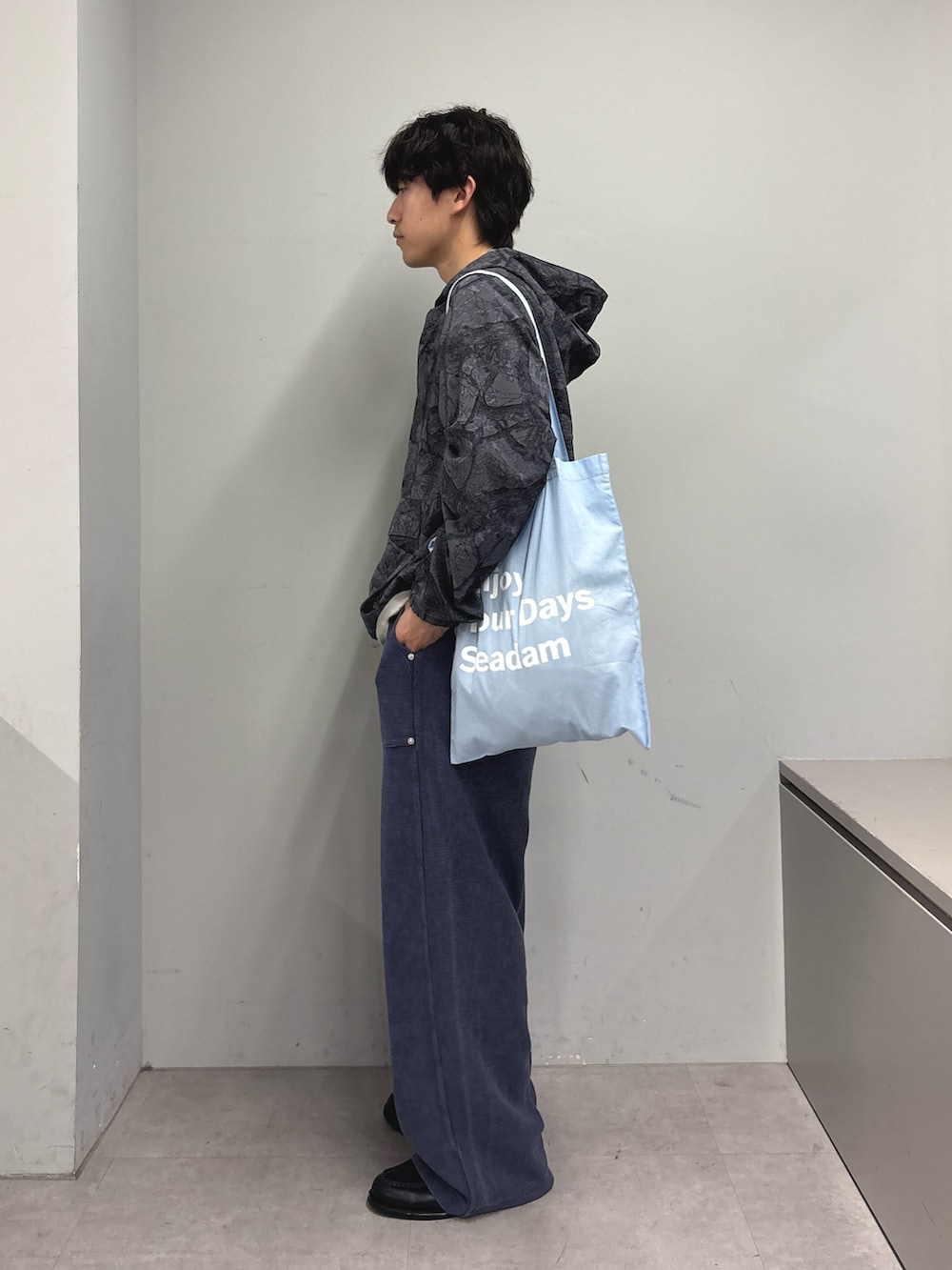 ブラック系のナイロンジャケット、ブルー系のトートバッグ、ブルー系のスウェットパンツを着用したメンズの春コーディネートの2枚目の写真