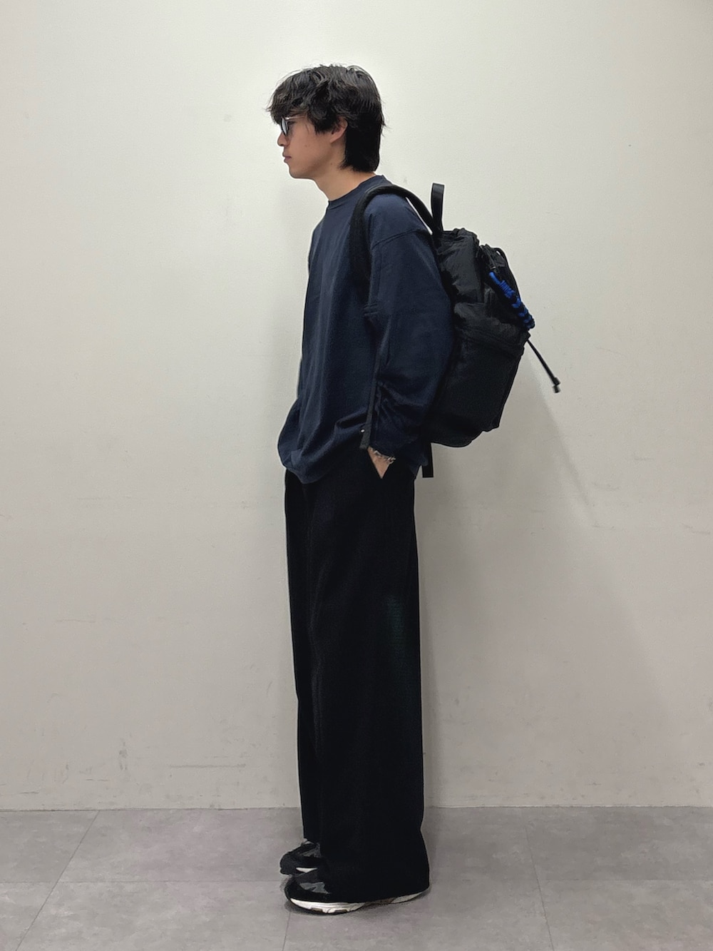 ブルー系のTシャツ/カットソー、ブラック系のバックパック/リュック、ブラック系のスラックスを着用したメンズの夏コーディネートの2枚目の写真