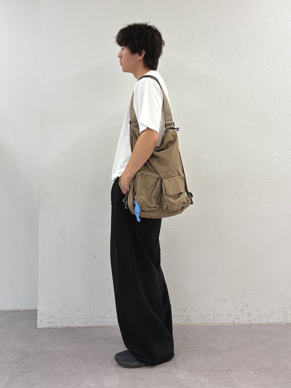ホワイト系のTシャツ/カットソー、ベージュ系のバックパック/リュック、ブラック系のスラックスを着用したメンズの夏コーディネートの2枚目の写真