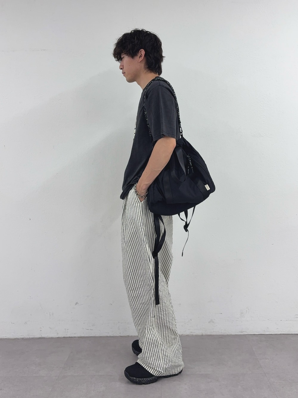 ブラック系のTシャツ/カットソー、ブラック系のトートバッグ、ホワイト系のその他パンツを着用したメンズの夏コーディネートの2枚目の写真