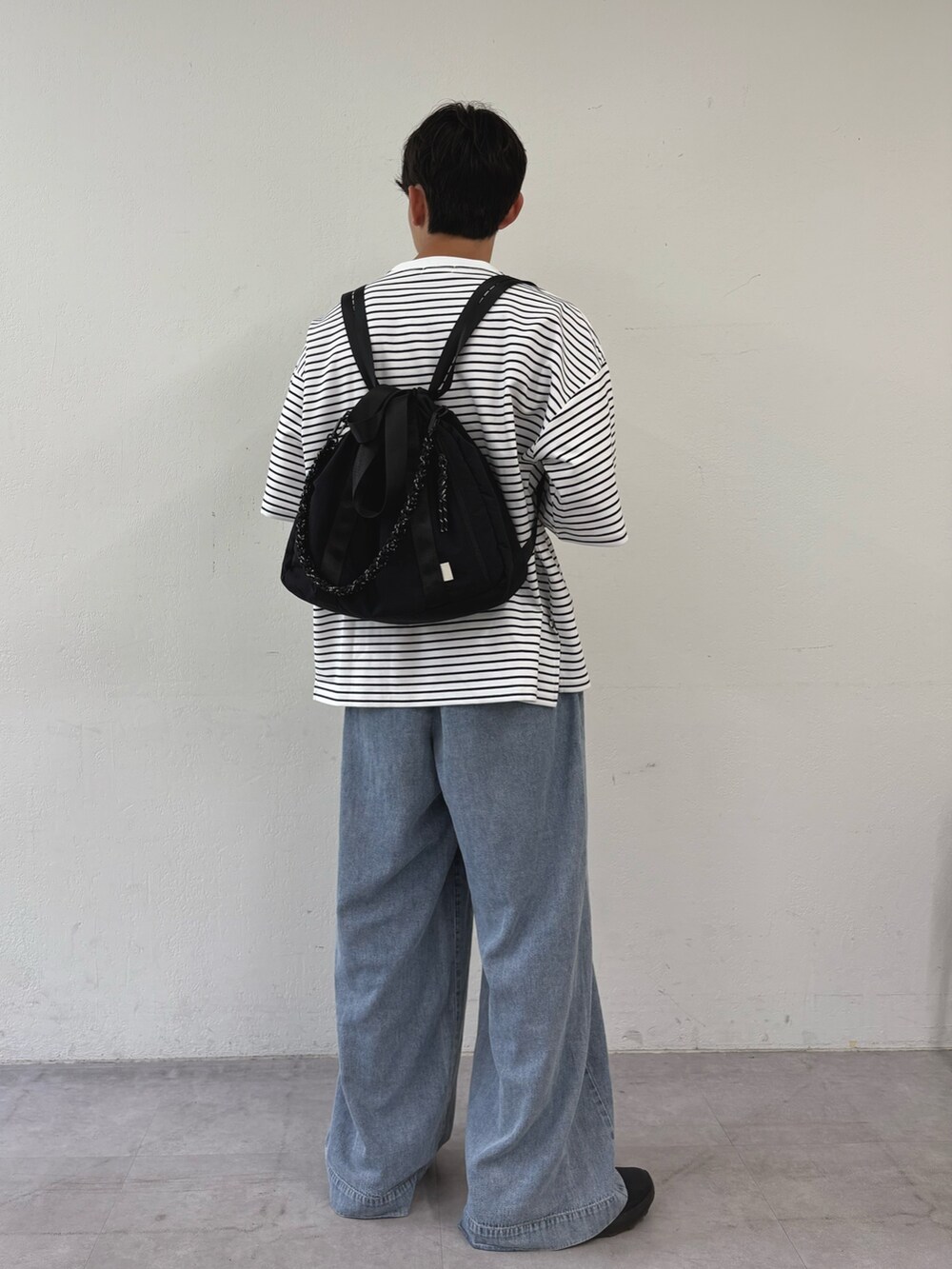 ホワイト系のTシャツ/カットソー、ブルー系のデニムパンツ、ブラック系のトートバッグを着用したメンズの秋コーディネートの3枚目の写真