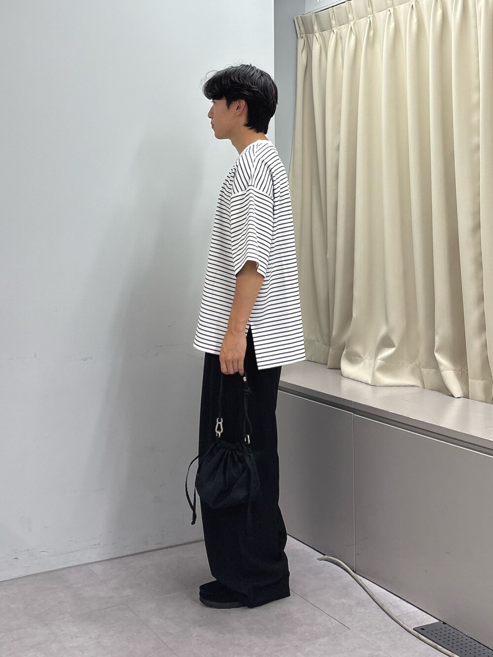 ホワイト系のTシャツ/カットソー、ブラック系のスラックス、ブラック系のショルダーバッグを着用したメンズの秋コーディネートの2枚目の写真