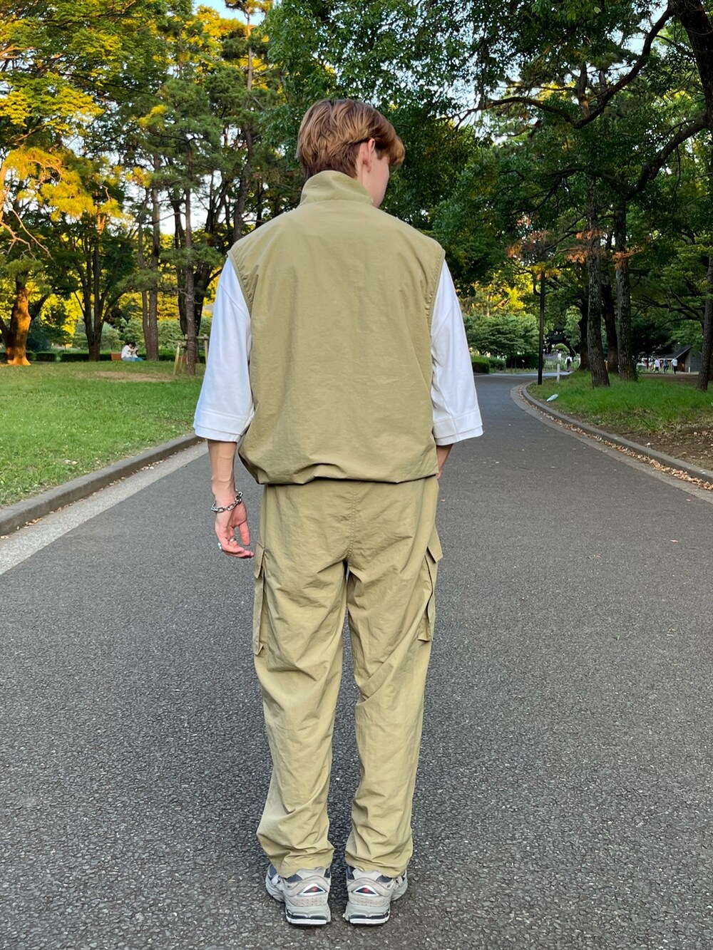 ベージュ系のベスト、グリーン系のカーゴパンツ、グレー系のスニーカーを着用したメンズの秋コーディネートの2枚目の写真