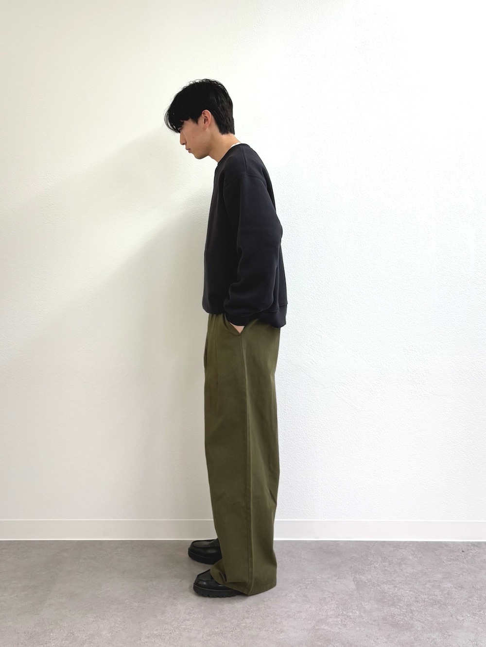 グリーン系のスラックス、ブラック系のローファー、グレー系のスウェットを着用したメンズの冬コーディネートの2枚目の写真