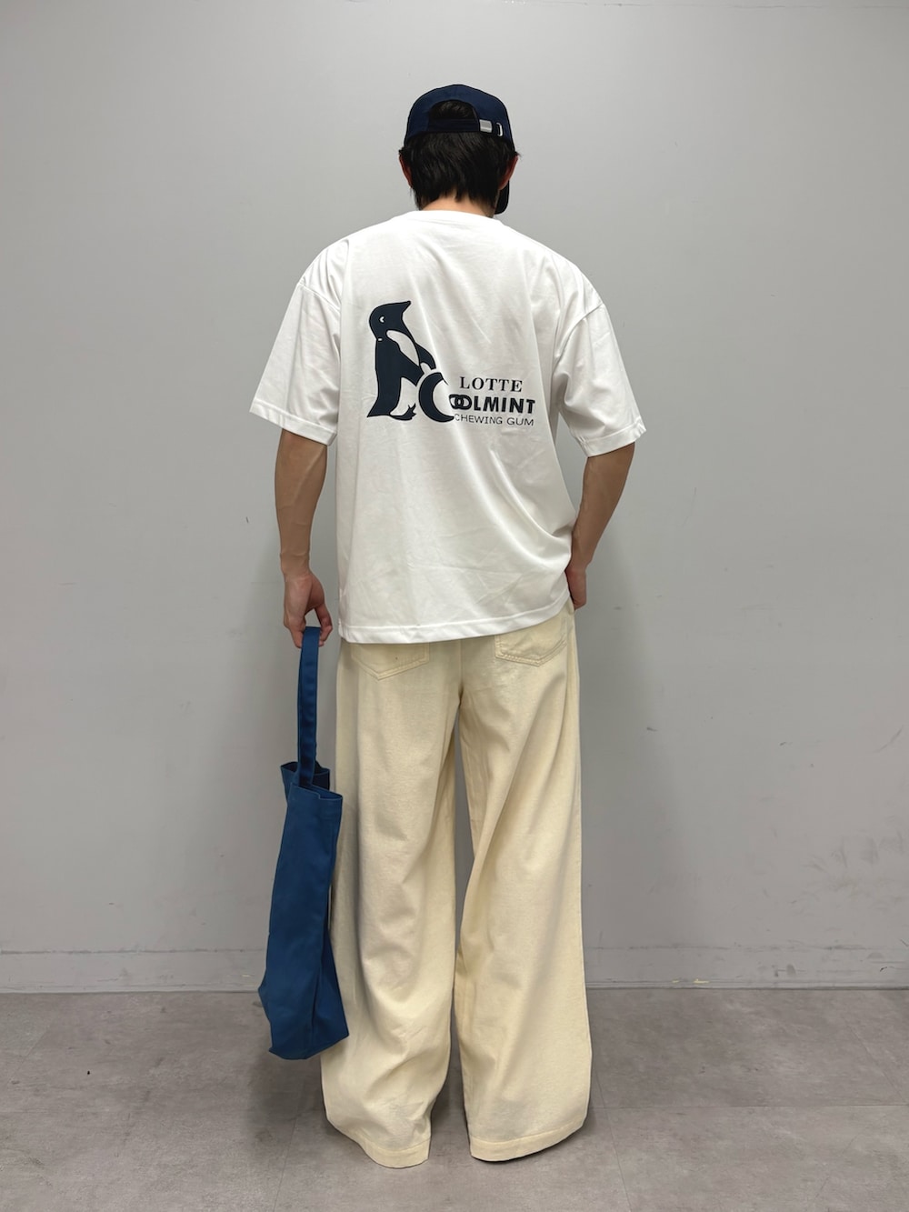 ブルー系のトートバッグ、ホワイト系のTシャツ/カットソー、ホワイト系のスラックスを着用したメンズの春コーディネートの3枚目の写真