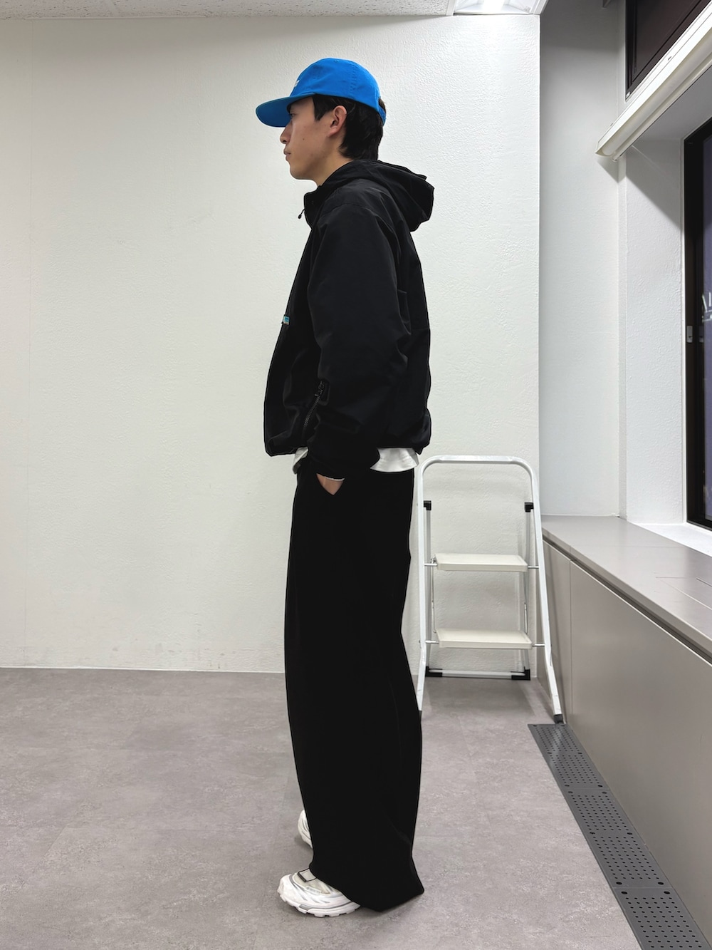 ブラック系のマウンテンパーカー、ブラック系のスラックス、ブルー系のキャップを着用したメンズの冬コーディネートの2枚目の写真