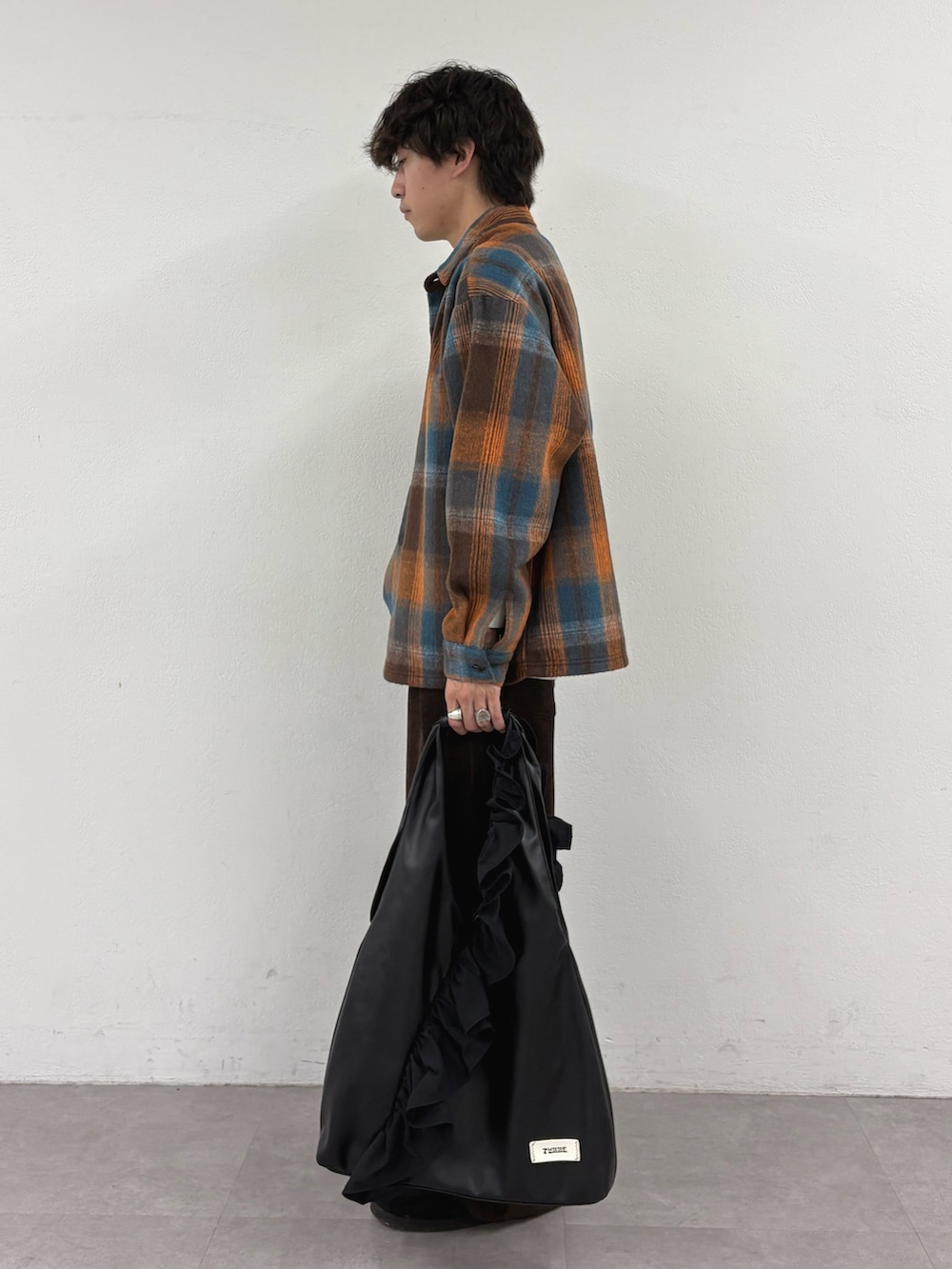 オレンジ系のシャツ/ブラウス、ブラウン系のその他パンツ、ブラック系のトートバッグを着用したメンズの秋コーディネートの2枚目の写真