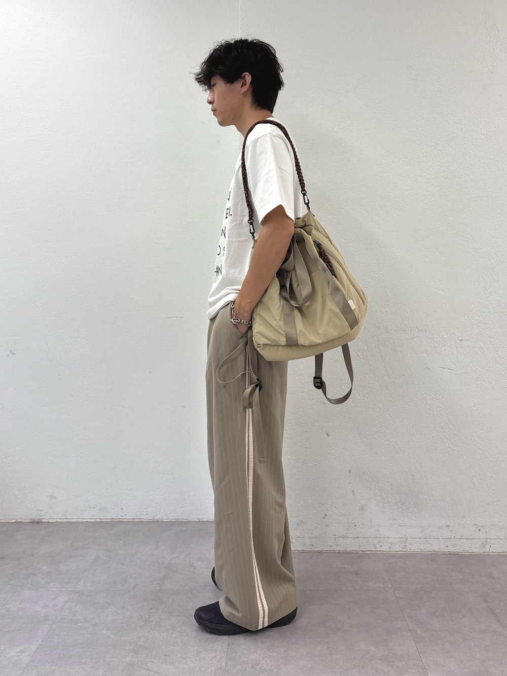 ホワイト系のTシャツ/カットソー、ベージュ系のトートバッグ、ベージュ系のスラックスを着用したメンズの夏コーディネートの2枚目の写真