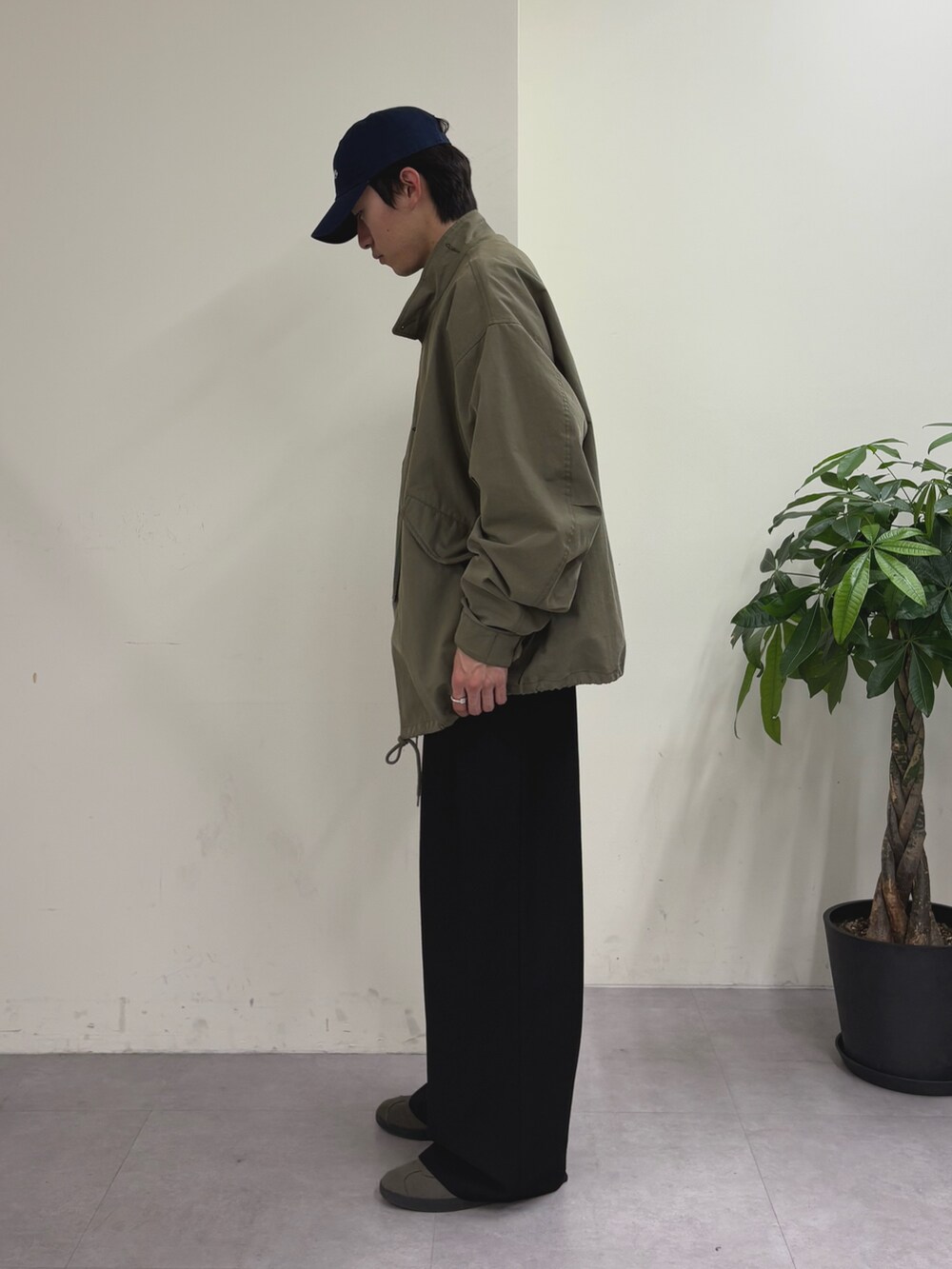 グリーン系のモッズコート、ブルー系のスウェット、ブラック系のスラックスを着用したメンズの春コーディネートの2枚目の写真