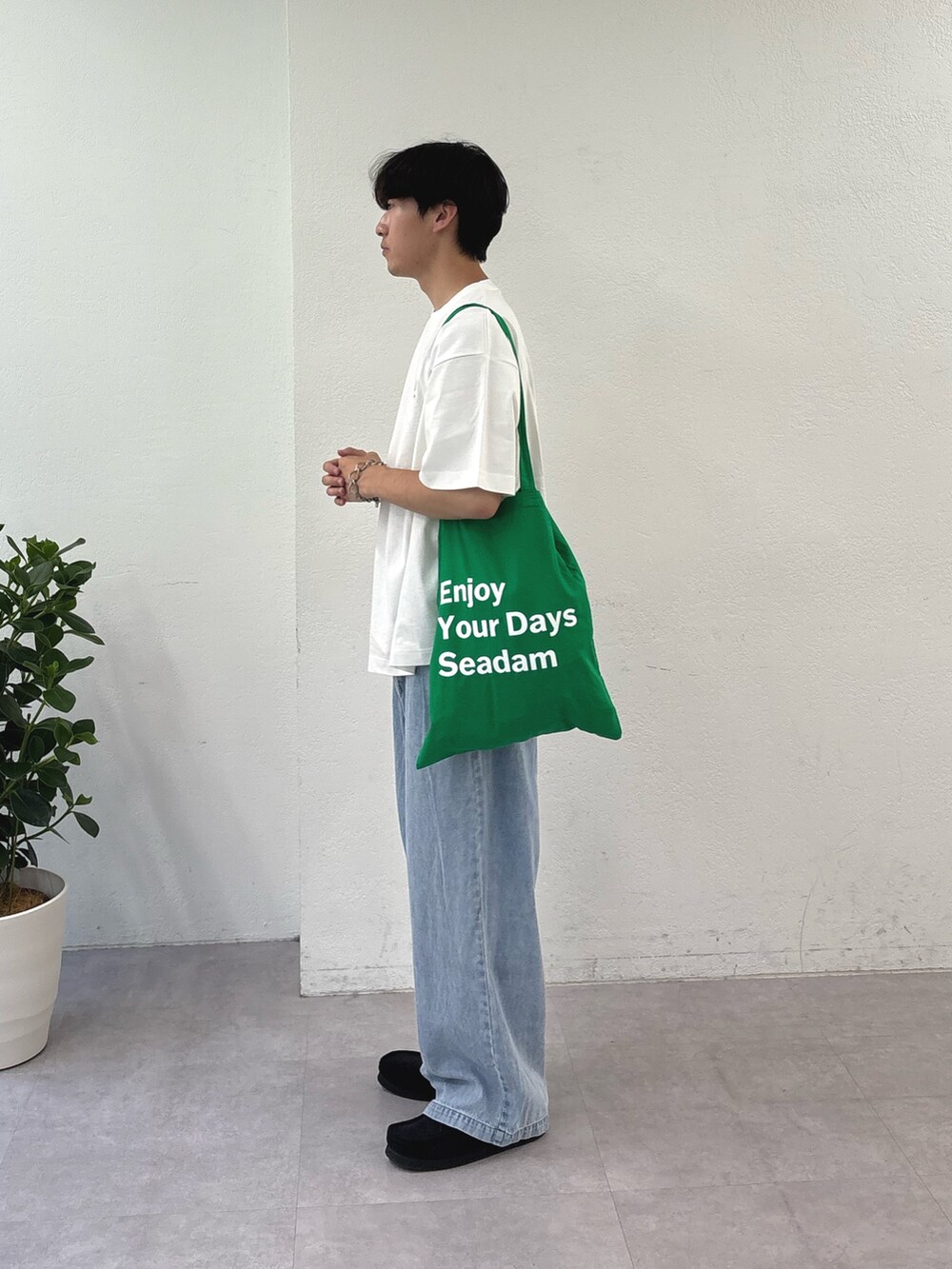 ホワイト系のTシャツ/カットソー、グリーン系のトートバッグ、ブルー系のデニムパンツを着用したメンズの夏コーディネートの2枚目の写真