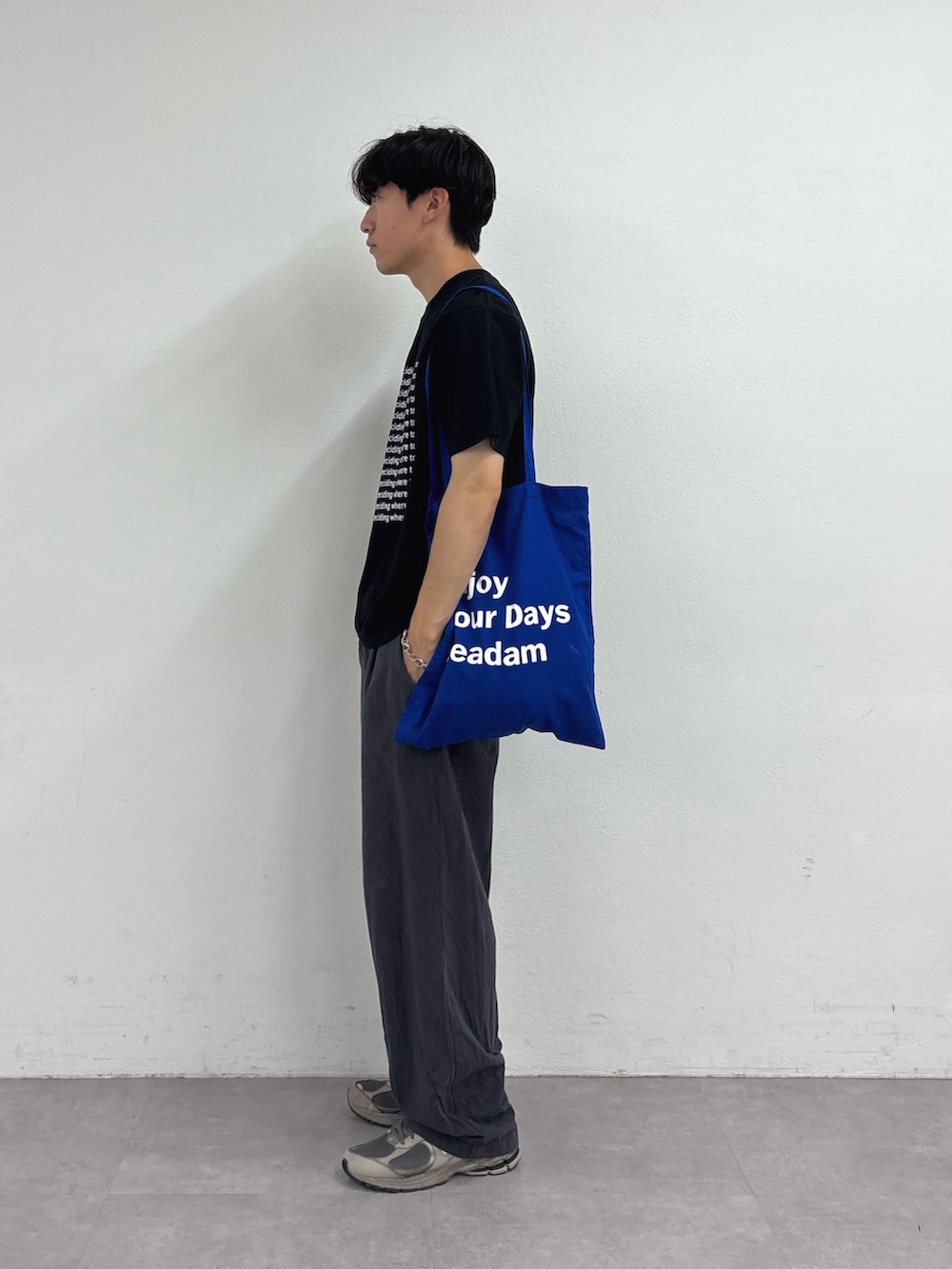 ブラック系のTシャツ/カットソー、ブルー系のトートバッグ、グレー系のチノパンツを着用したメンズの夏コーディネートの2枚目の写真