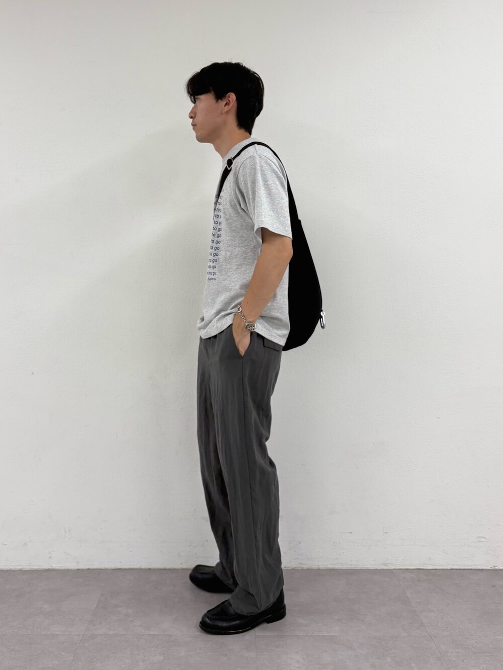 グレー系のTシャツ/カットソー、ブラック系のショルダーバッグ、グレー系のスラックスを着用したメンズの夏コーディネートの2枚目の写真