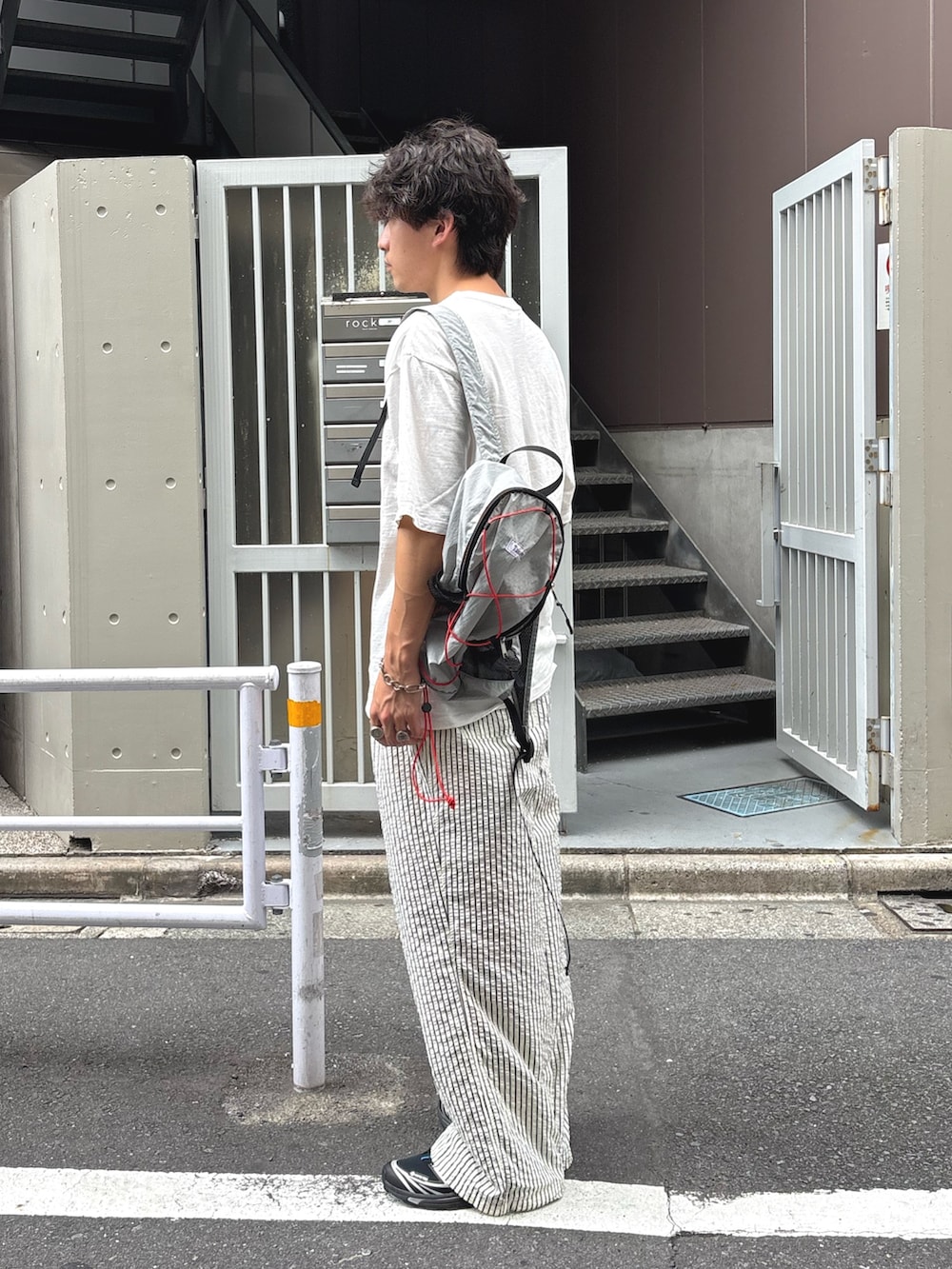 ホワイト系のTシャツ/カットソー、グレー系のバックパック/リュック、ホワイト系のその他パンツを着用したメンズの秋コーディネートの2枚目の写真