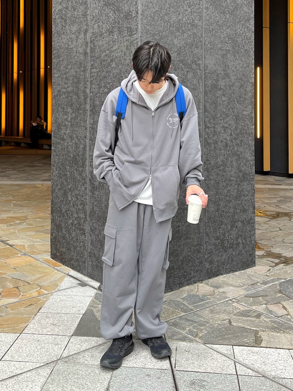 ブラック系のスニーカー、グレー系のトップス、ブルー系のバックパック/リュックを着用したメンズの冬コーディネートの2枚目の写真