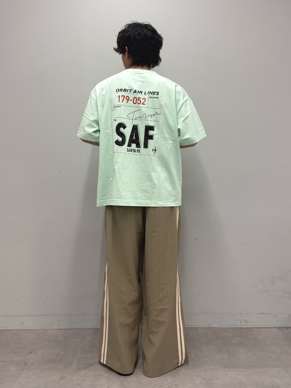 グリーン系のTシャツ/カットソー、ベージュ系のスラックスを着用したメンズの春コーディネートの3枚目の写真