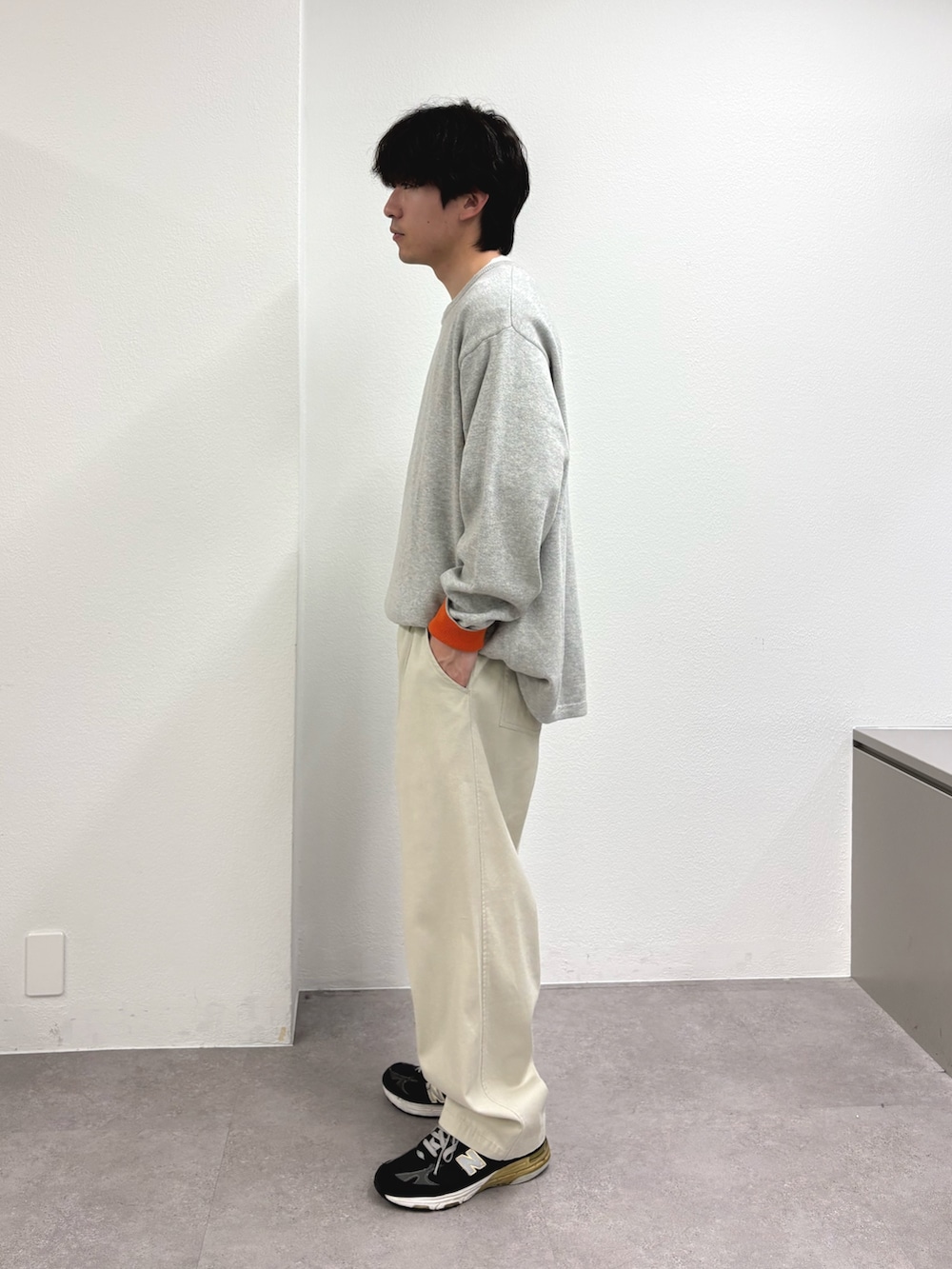 グレー系のニット/セーター、ホワイト系のチノパンツを着用したメンズの春コーディネートの2枚目の写真