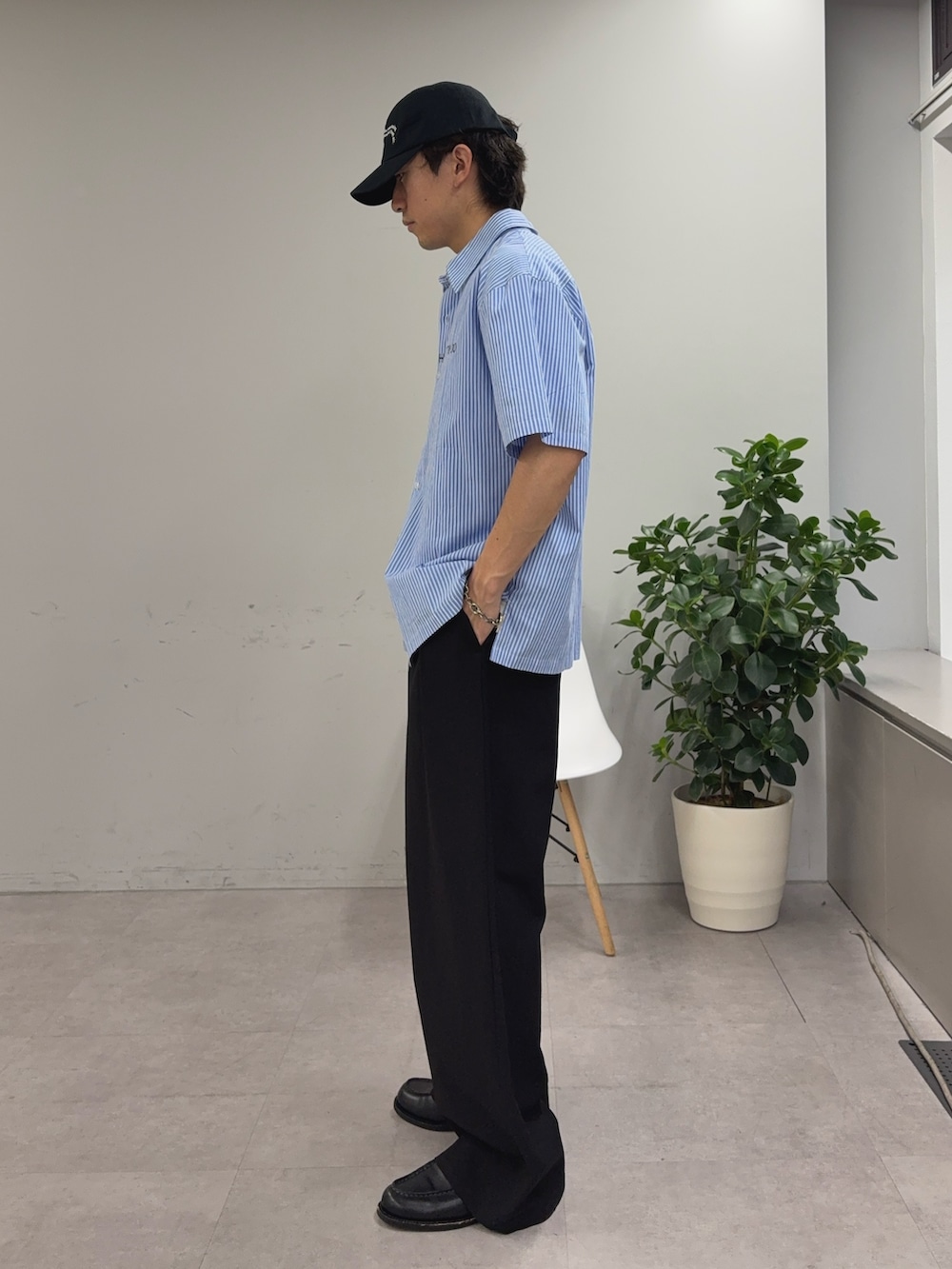 ブルー系のシャツ/ブラウス、ブラック系のスラックス、ブラック系のキャップを着用したメンズの春コーディネートの2枚目の写真