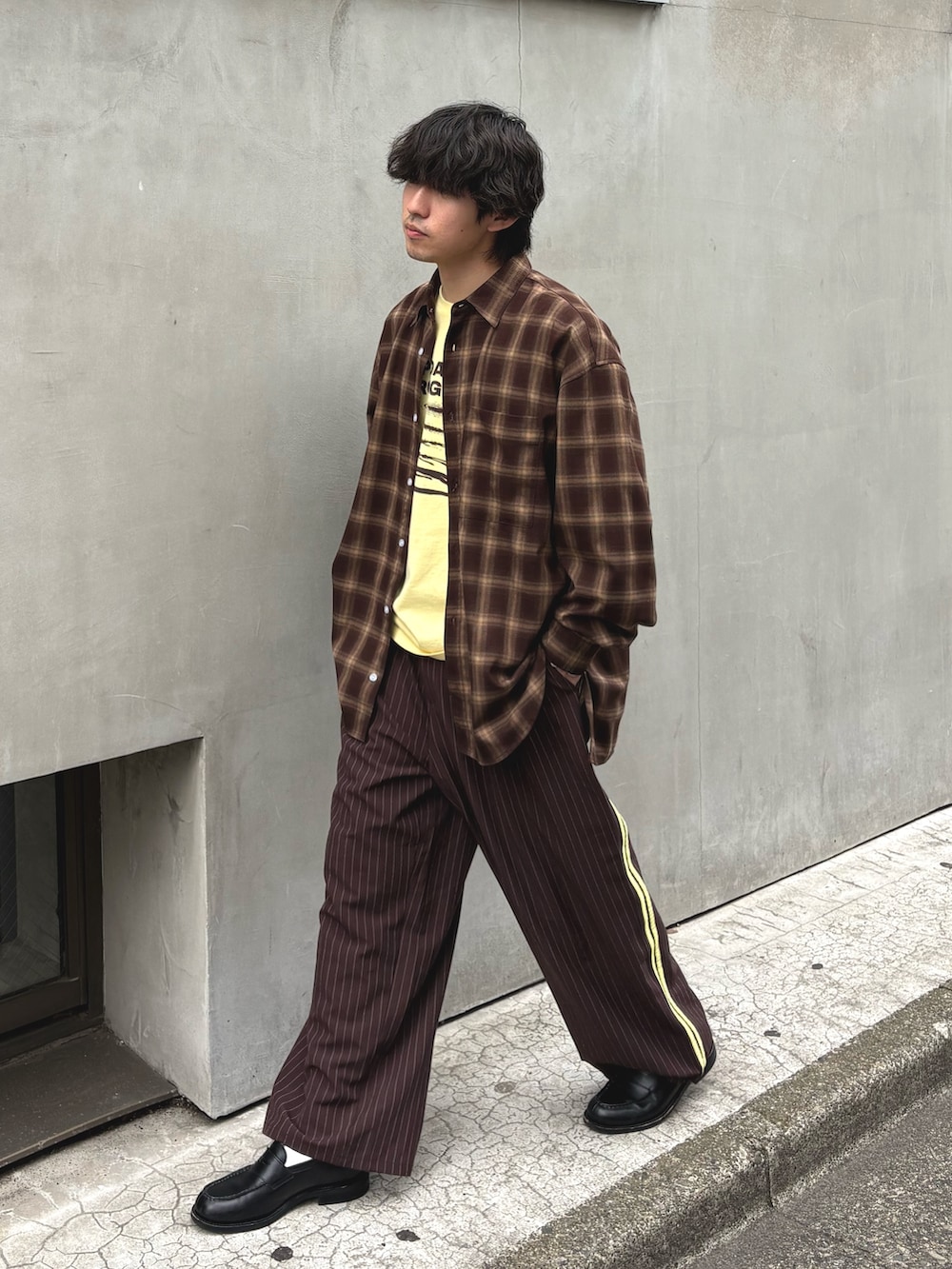 ブラウン系のシャツ/ブラウス、イエロー系のTシャツ/カットソー、ブラウン系のスラックスを着用したメンズの春コーディネートの2枚目の写真