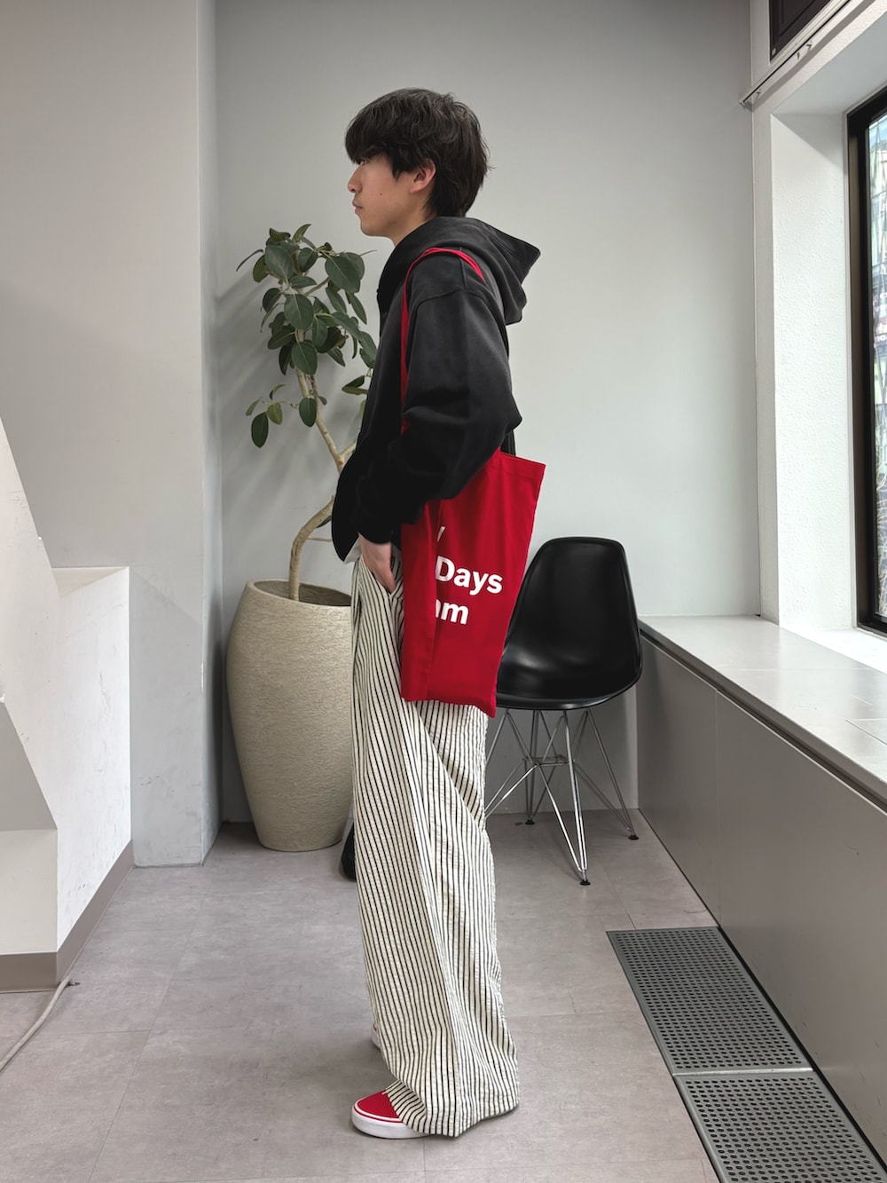 ブラック系のパーカー、レッド系のトートバッグ、ホワイト系のその他パンツを着用したメンズの春コーディネートの2枚目の写真
