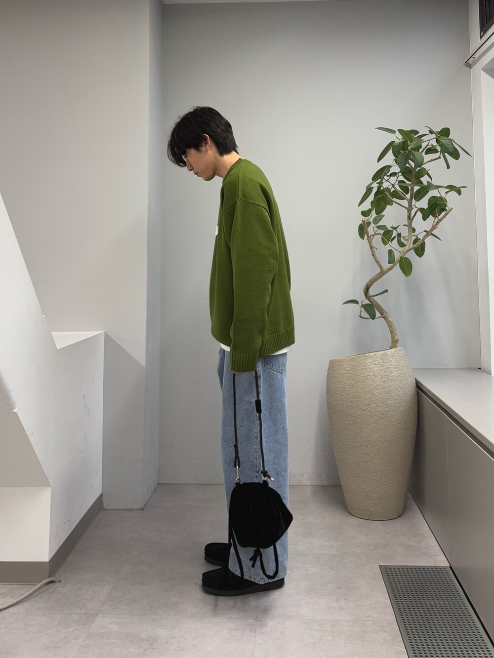 グリーン系のニット/セーター、ブルー系のデニムパンツ、ブラック系のショルダーバッグを着用したメンズの春コーディネートの2枚目の写真