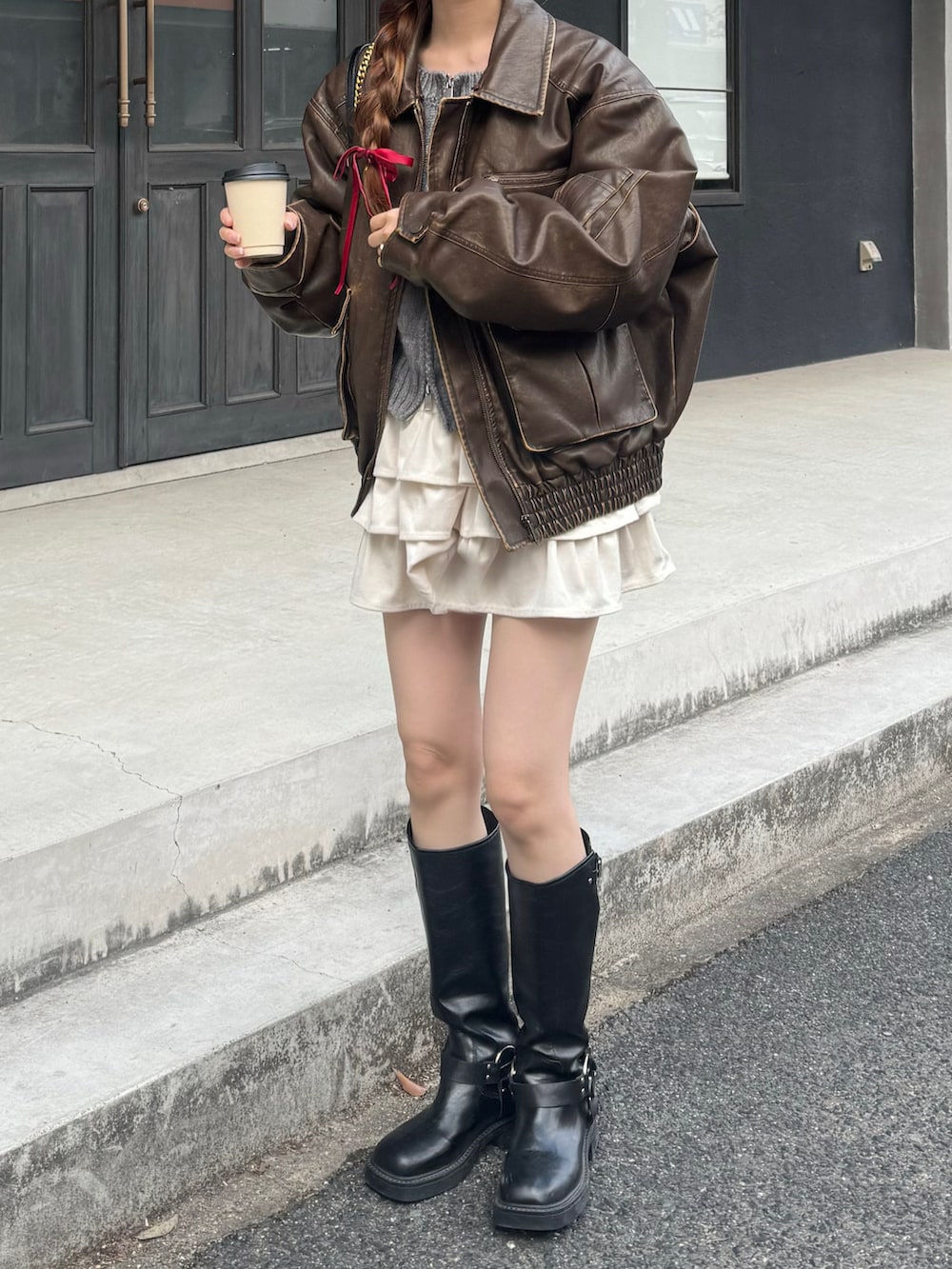 ブラウン系のブルゾン、ホワイト系のスカート、ブラック系のブーツを着用したレディースの秋コーディネートの2枚目の写真