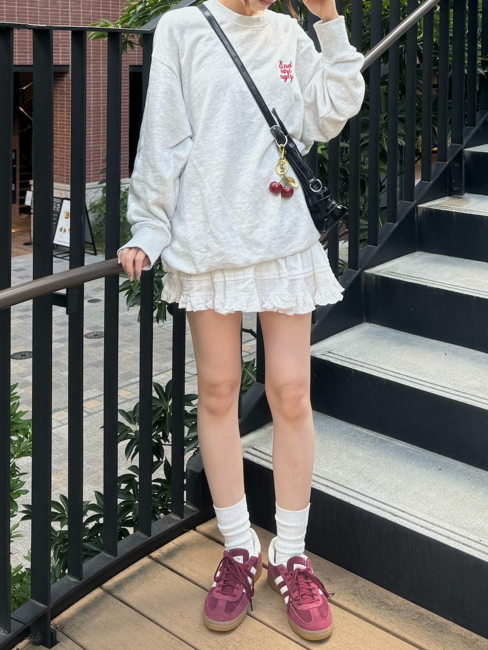 グレー系のスウェット、ブラック系のバッグ、ピンク系のスニーカーを着用したレディースの秋コーディネートの2枚目の写真