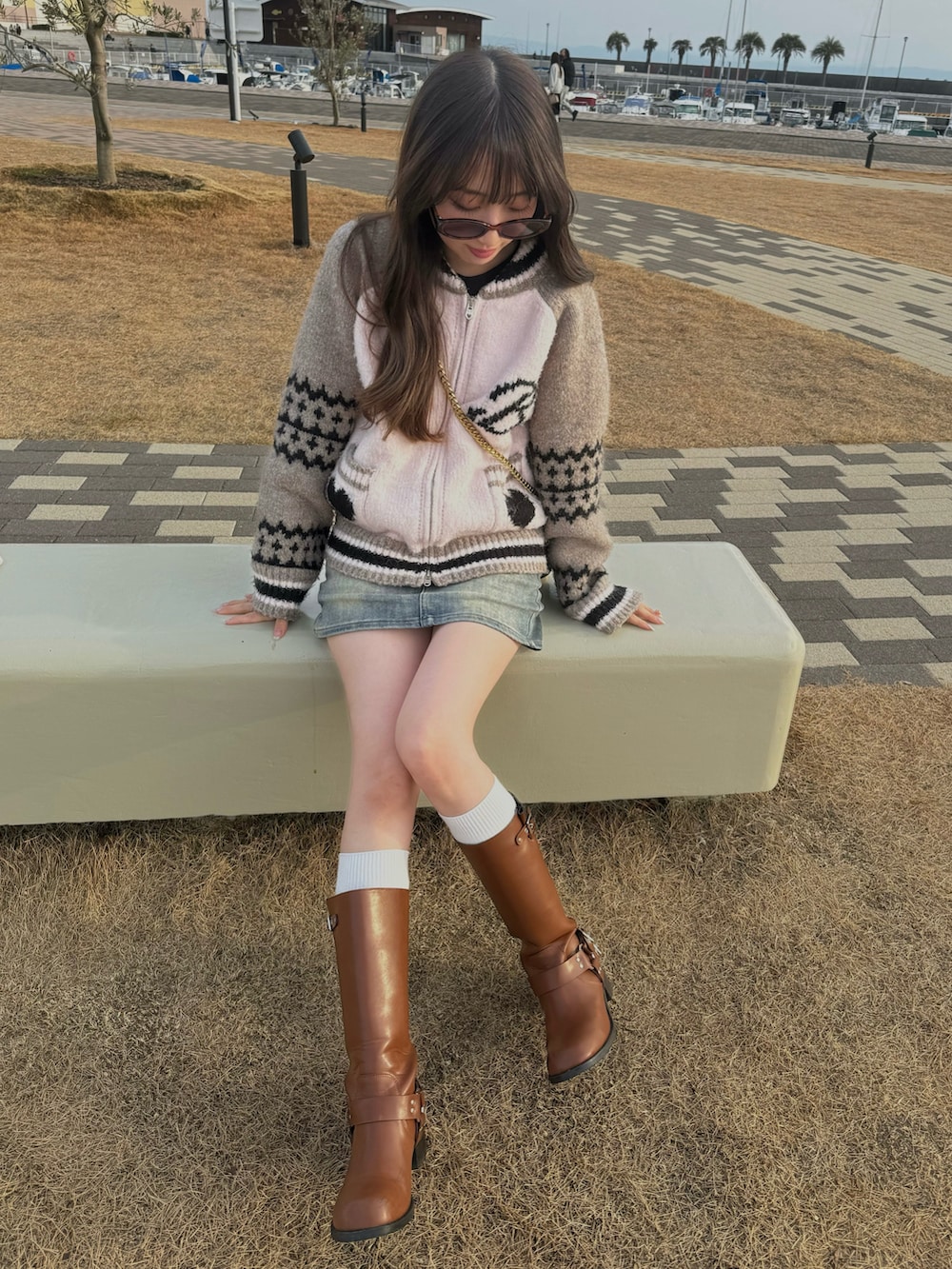 ピンク系のカーディガン/ボレロ、ブルー系のデニムスカート、ブラウン系のブーツを着用したレディースの冬コーディネートの2枚目の写真