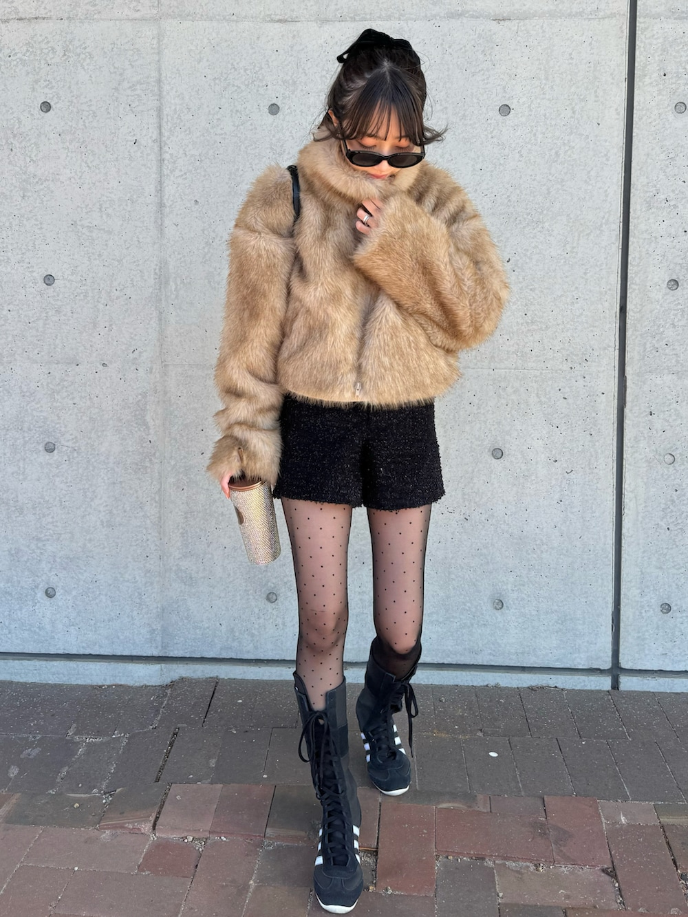 ブラウン系のブルゾン、ブラック系のパンツ、ブラック系のスニーカーを着用したレディースの冬コーディネートの3枚目の写真