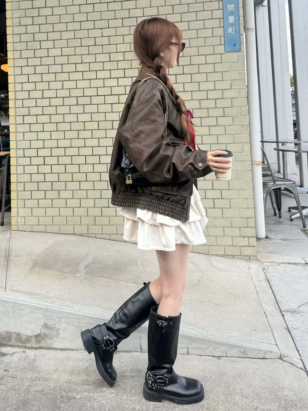 ブラウン系のブルゾン、ホワイト系のスカート、ブラック系のブーツを着用したレディースの秋コーディネートの3枚目の写真