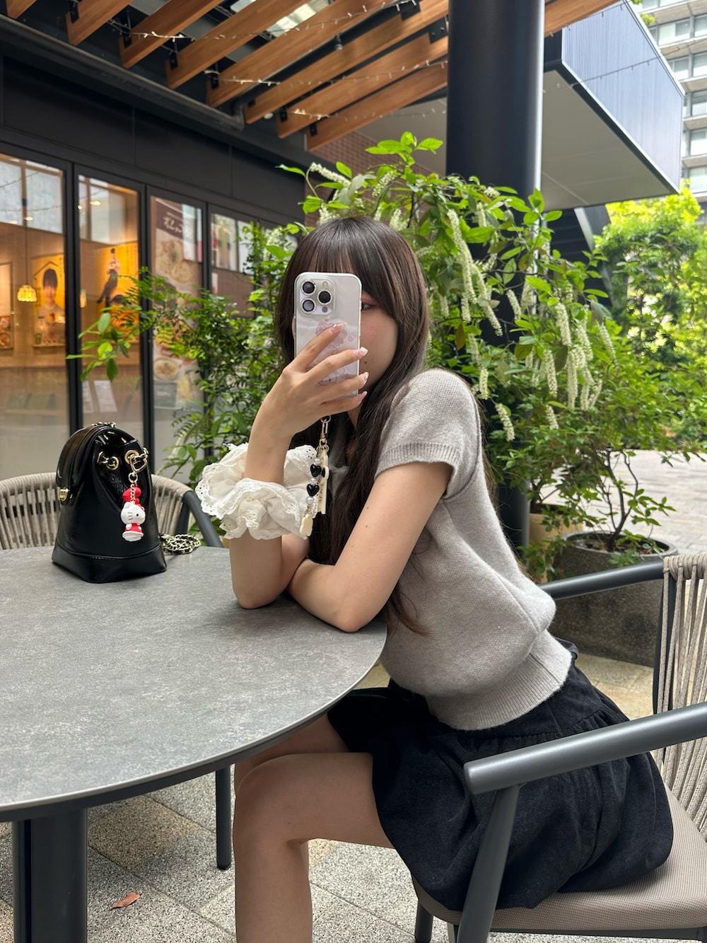 グレー系のニット/セーター、ブラック系のスカート、シルバー系のパンプスを着用したレディースの春コーディネートの3枚目の写真