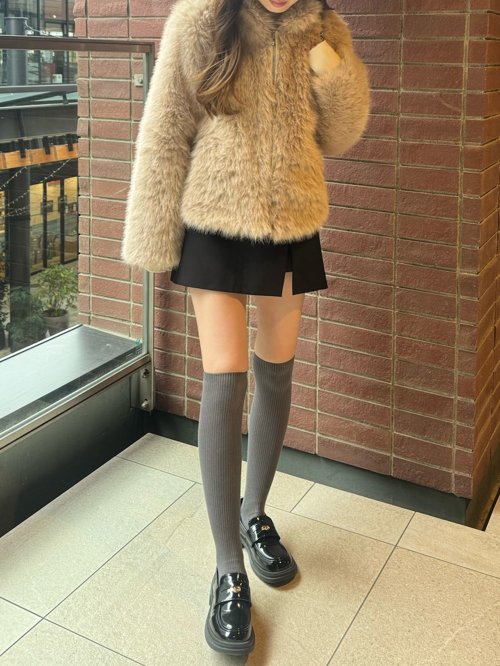 ベージュ系のジャケット/アウター、ブラック系のバックパック/リュック、ブラック系のローファーを着用したレディースの冬コーディネートの2枚目の写真