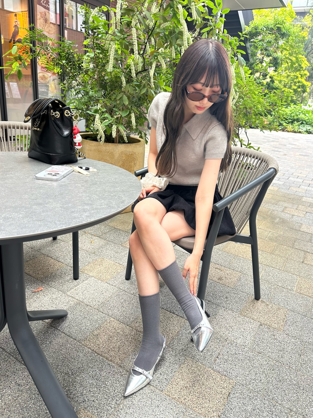 グレー系のニット/セーター、ブラック系のスカート、シルバー系のパンプスを着用したレディースの春コーディネートの2枚目の写真