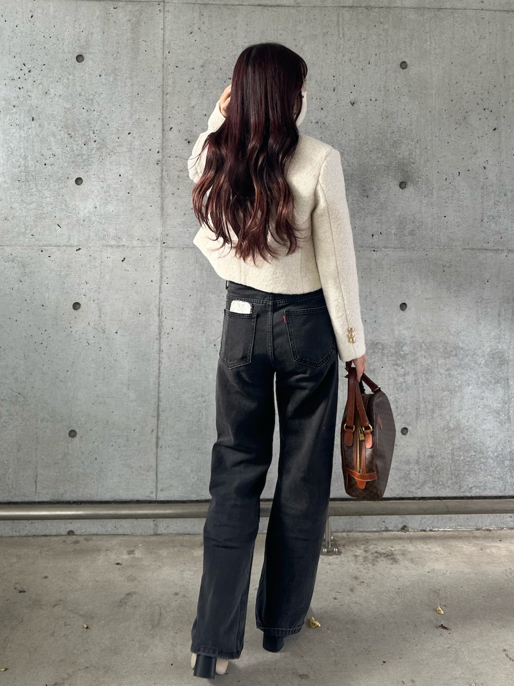 ホワイト系のジャケット/アウター、ブラック系のデニムパンツ、ブラウン系のバッグを着用したレディースの冬コーディネートの3枚目の写真