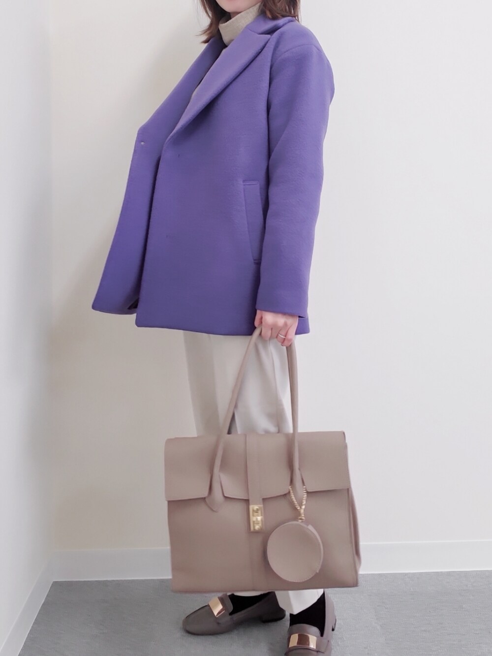 ベージュ系のビジネスバッグ、パープル系のステンカラーコート、グレー系のローファーを着用したレディースの冬コーディネートの2枚目の写真