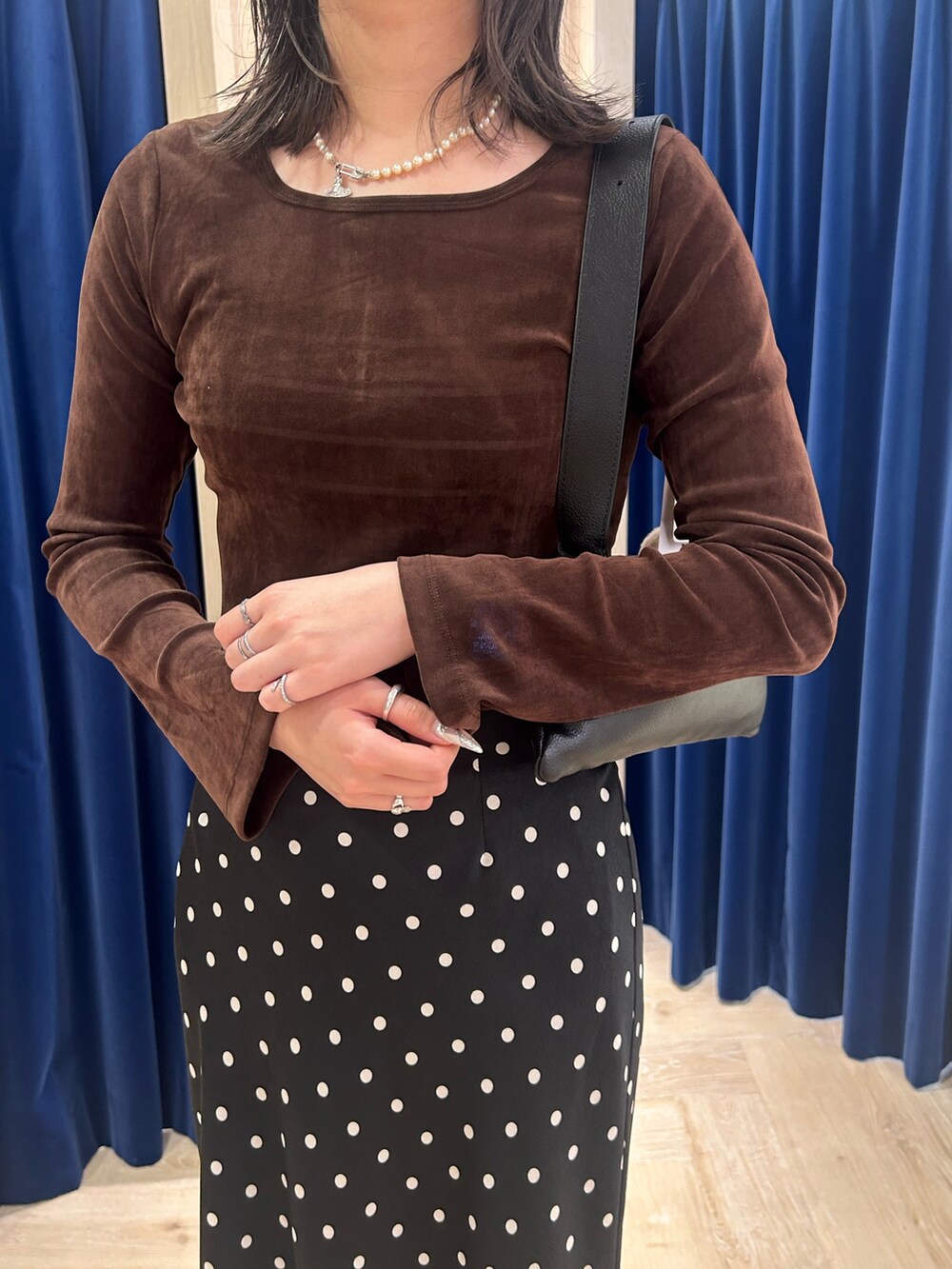 ブラウン系のTシャツ/カットソー、ブラック系のスカート、ブラック系のショルダーバッグを着用したレディースの秋コーディネートの2枚目の写真