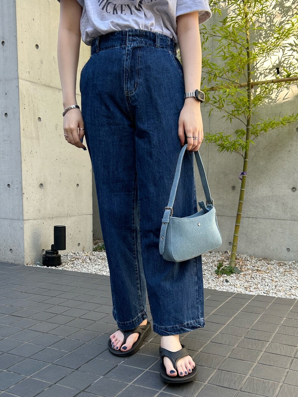 ブルー系のデニムパンツ、ブルー系のハンドバッグ、グレー系のTシャツ/カットソーを着用したレディースの夏コーディネートの3枚目の写真
